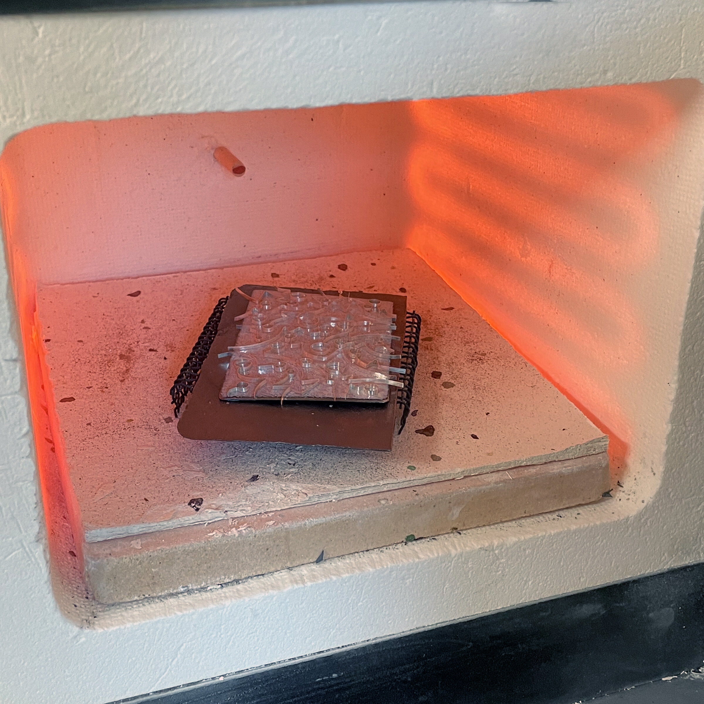  The piece is returned to the kiln, where the glue is burned off, and the melted glass traps the wires. 