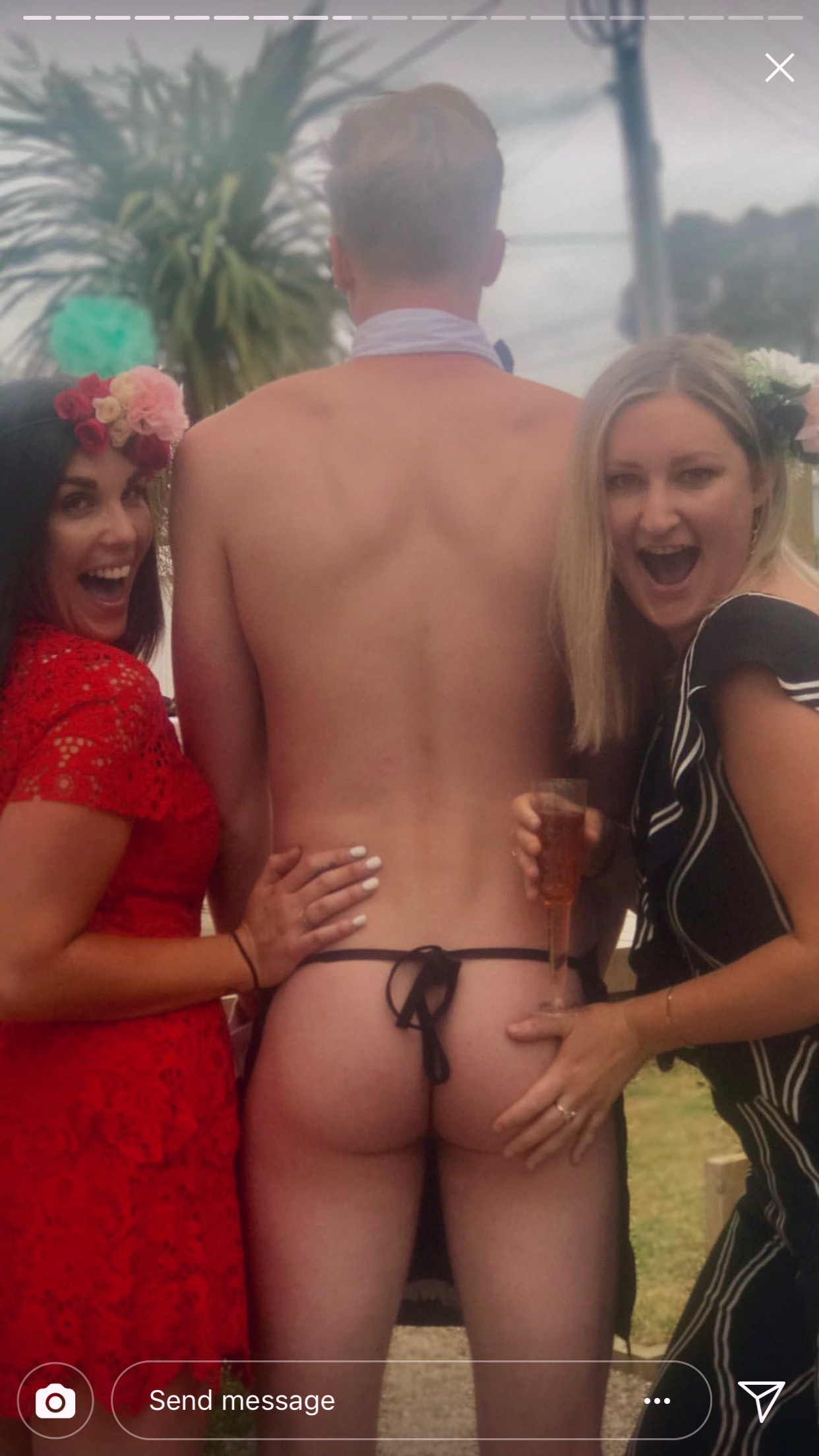 Bridesmaids pose with topless waiter's bare buns