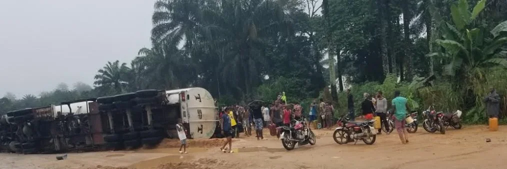 Youths risk their lives to grab petrol from a fallen vehicle.