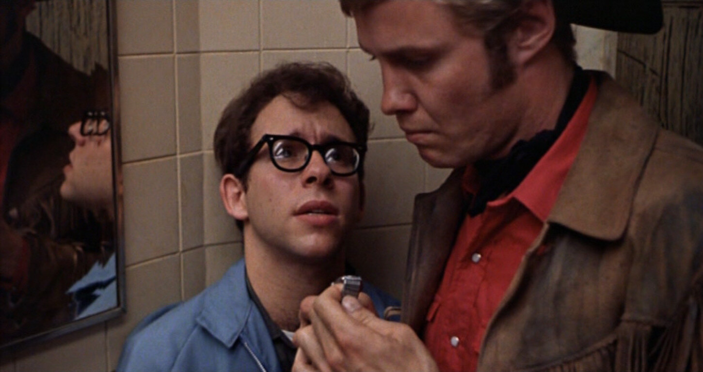 Joe solicits a man in a movie theater bathroom