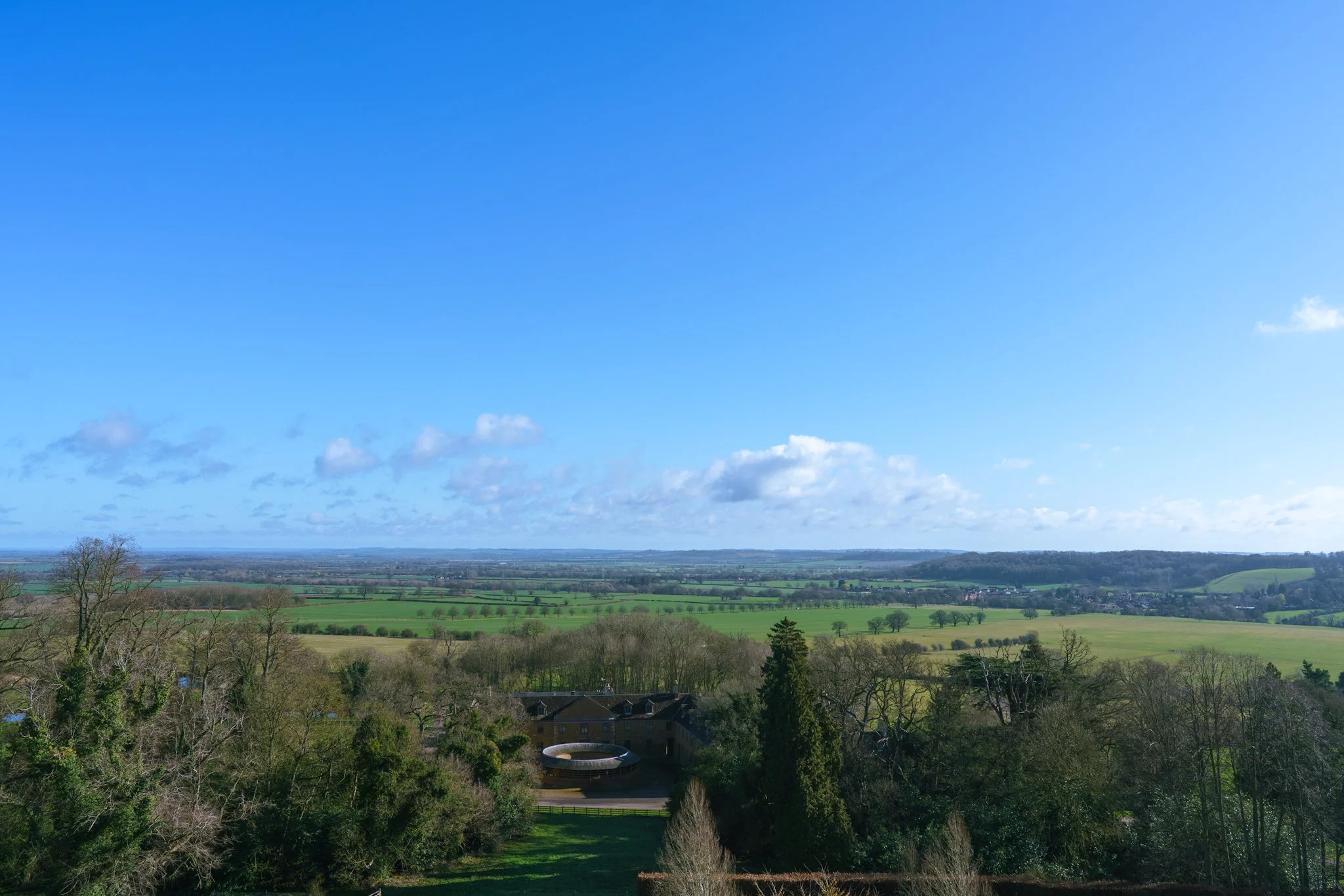 Panoramic view from Belvoir Castle over the stunning Vale of Belvoir in Leicestershire – rolling green fields, countryside vistas, and blue sky as a magical fairytale wedding backdrop. Photo by MAC Photography.