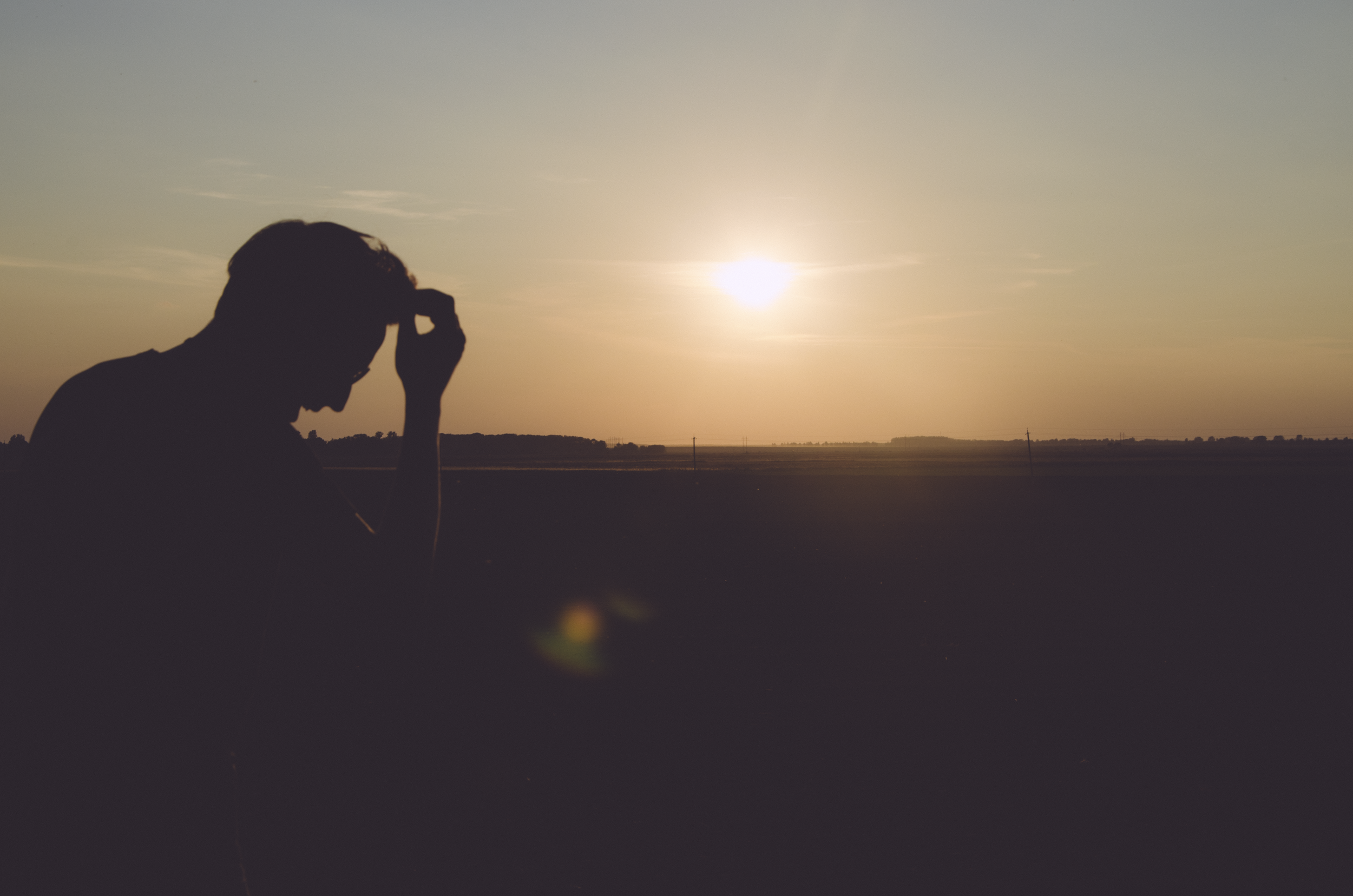 a silhouette of a man in front of a setting sun