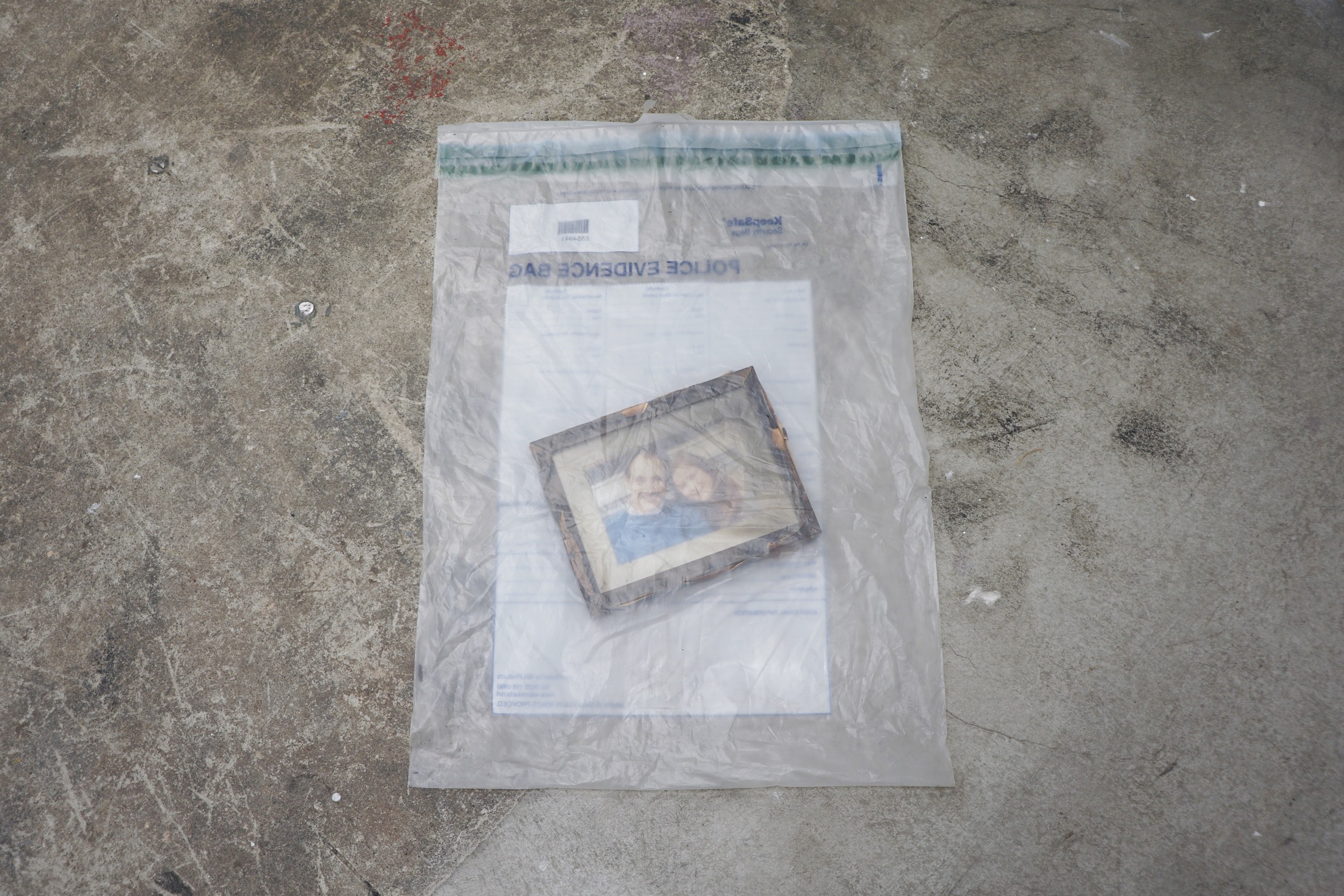  Anthony Discenza  Untitled (Burned Photograph) , 2017 Partially charred framed photo in plastic evidence bag used in production of 2011 film  Blitz  