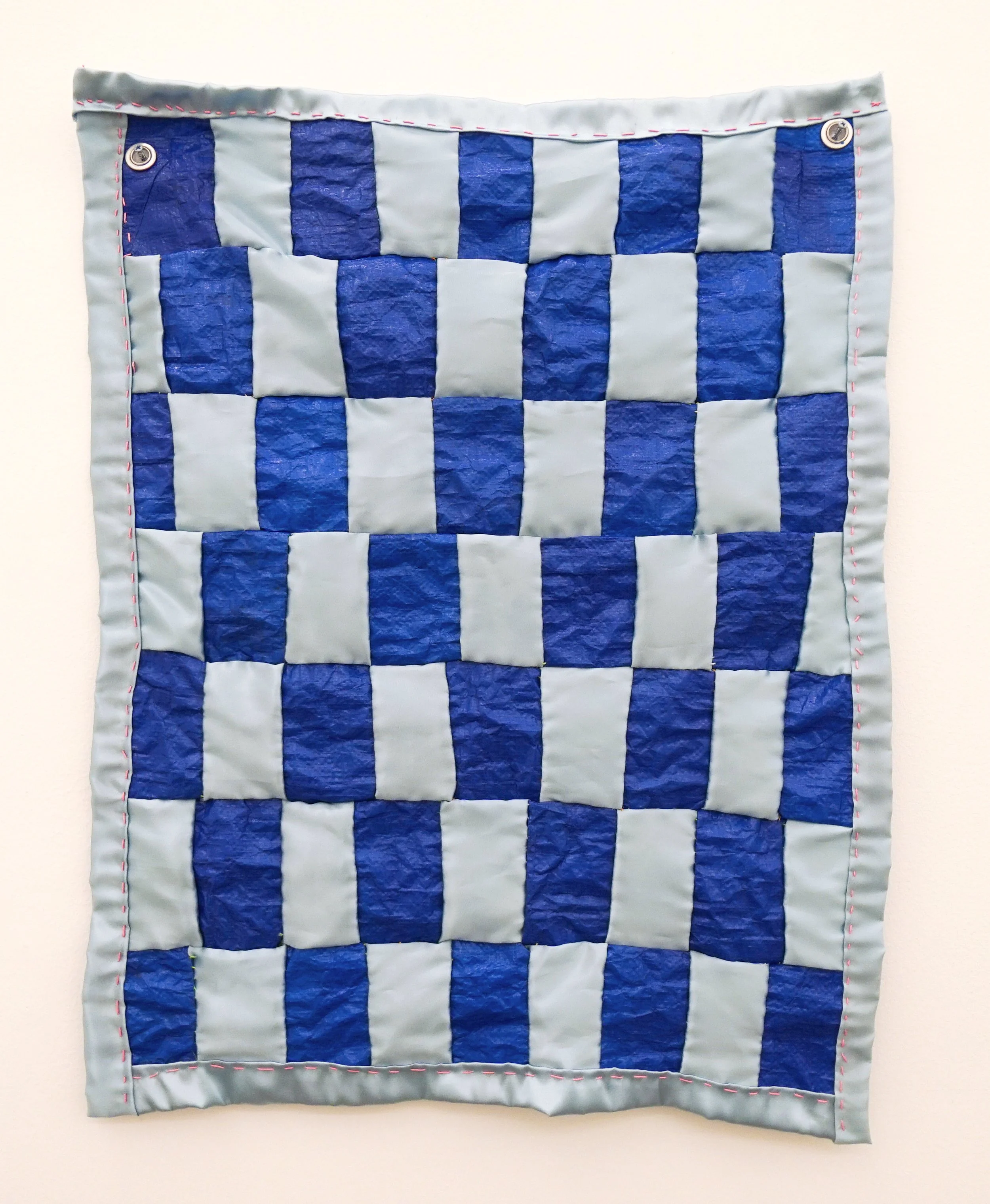  Kate Rhoades  Bad Back Baby Blanket , 2025 Stolen tarp, blue satin, embroidery floss 30 x 22 inches 