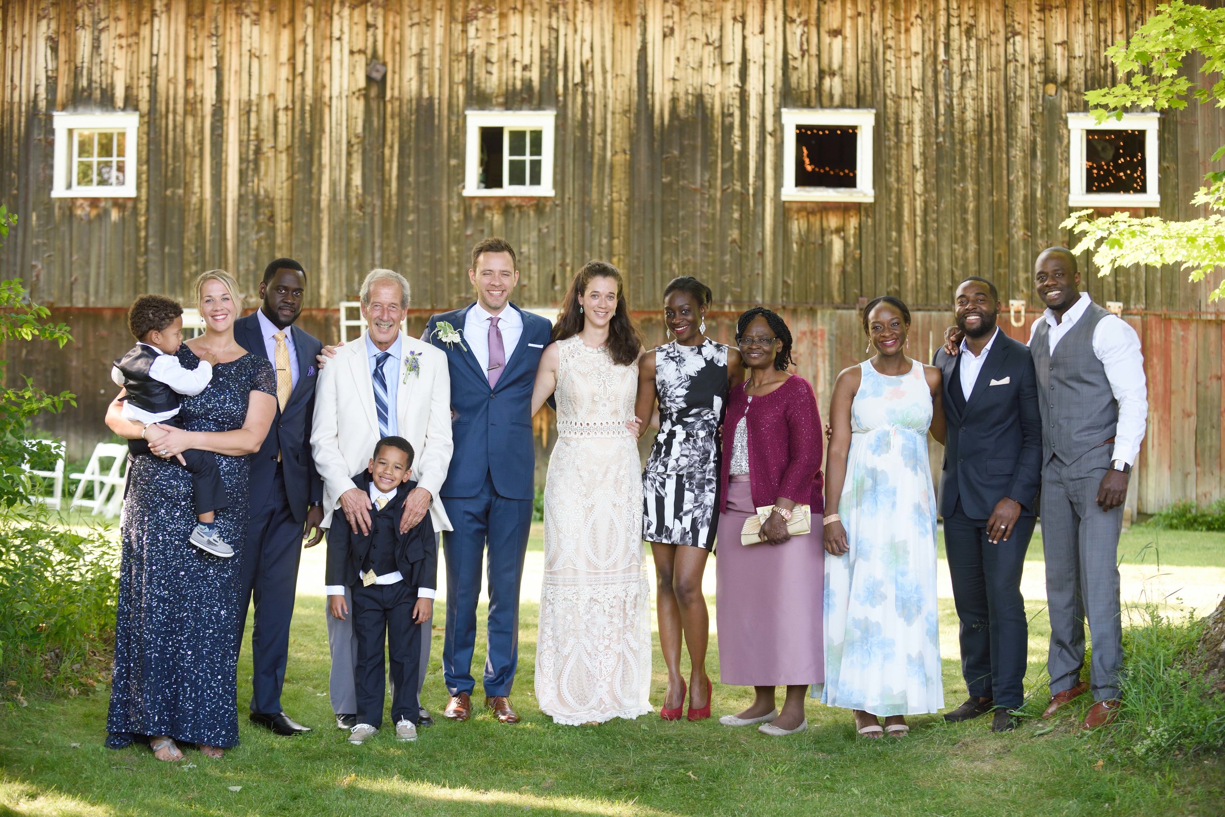 A wedding party standing in front of a rustic barn