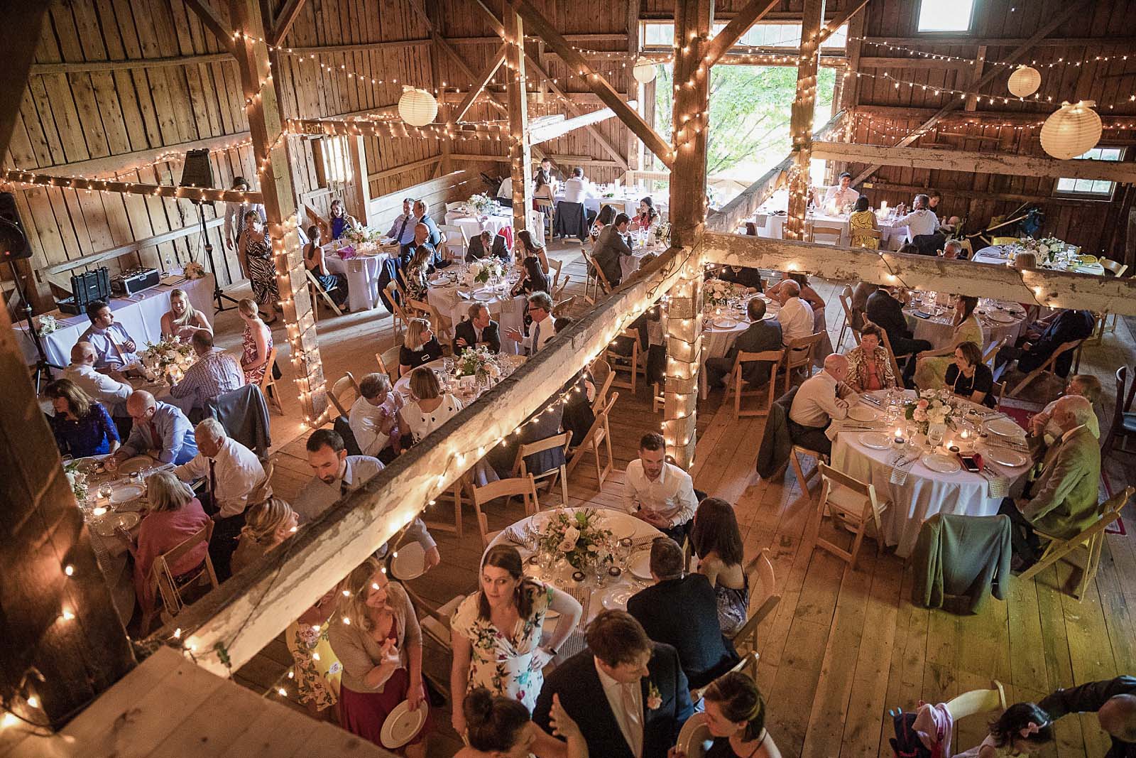 A lit barn filled with guests eating and talking