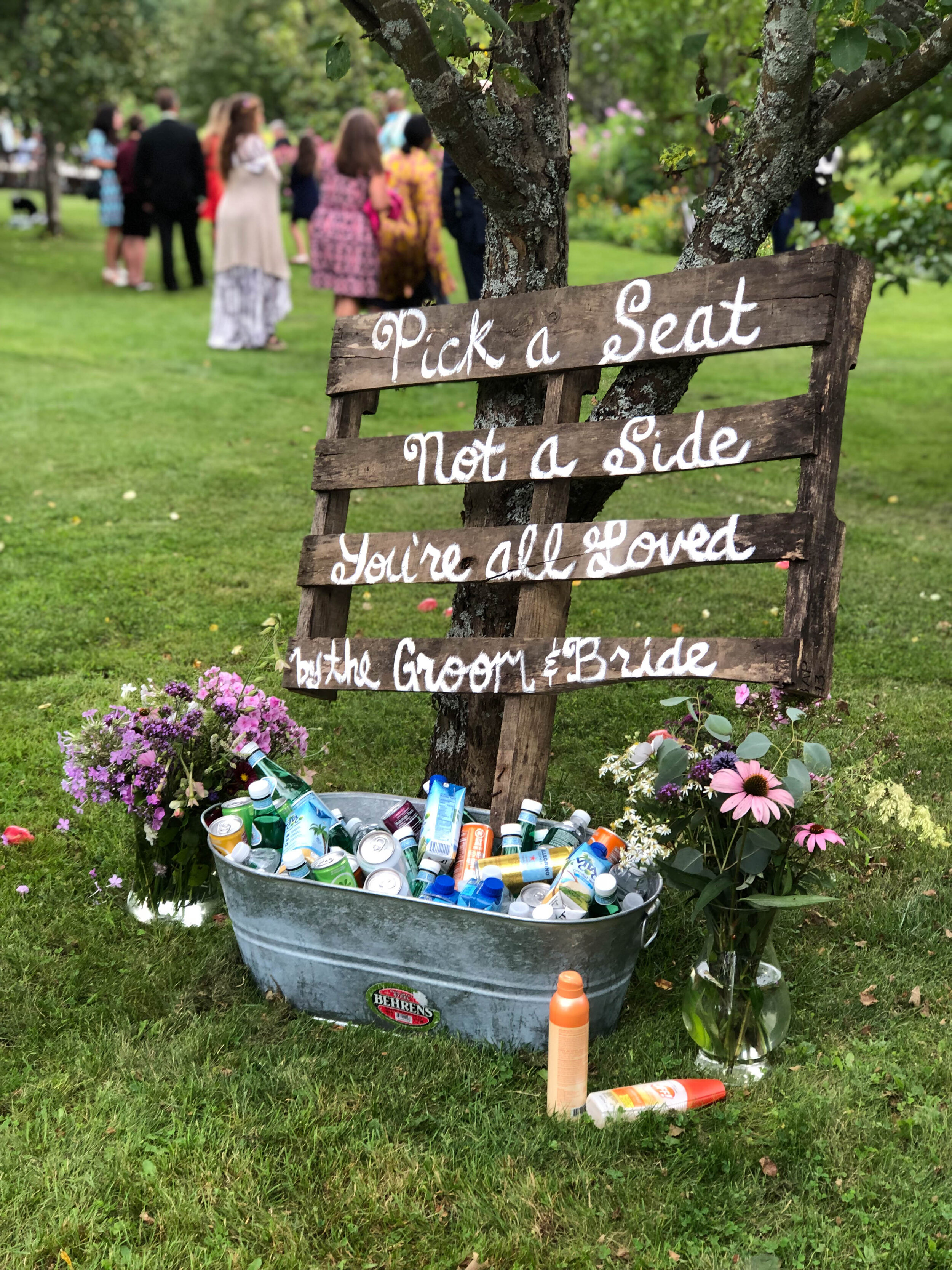A sign written on rustic wood set in a metal tub full of drinks
