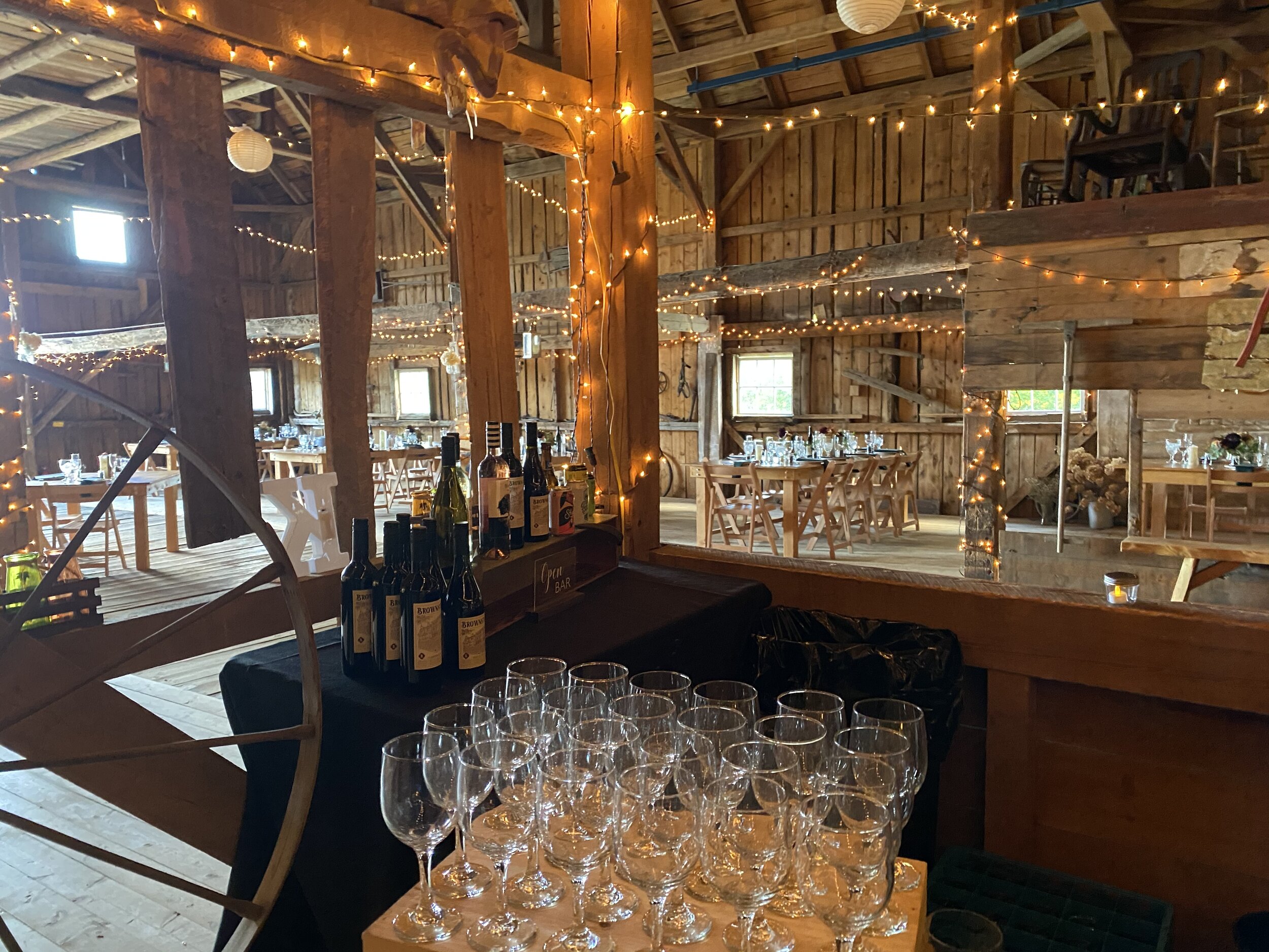 Wineglasses set up at the bar in a twinkle lit barn getting ready for an event