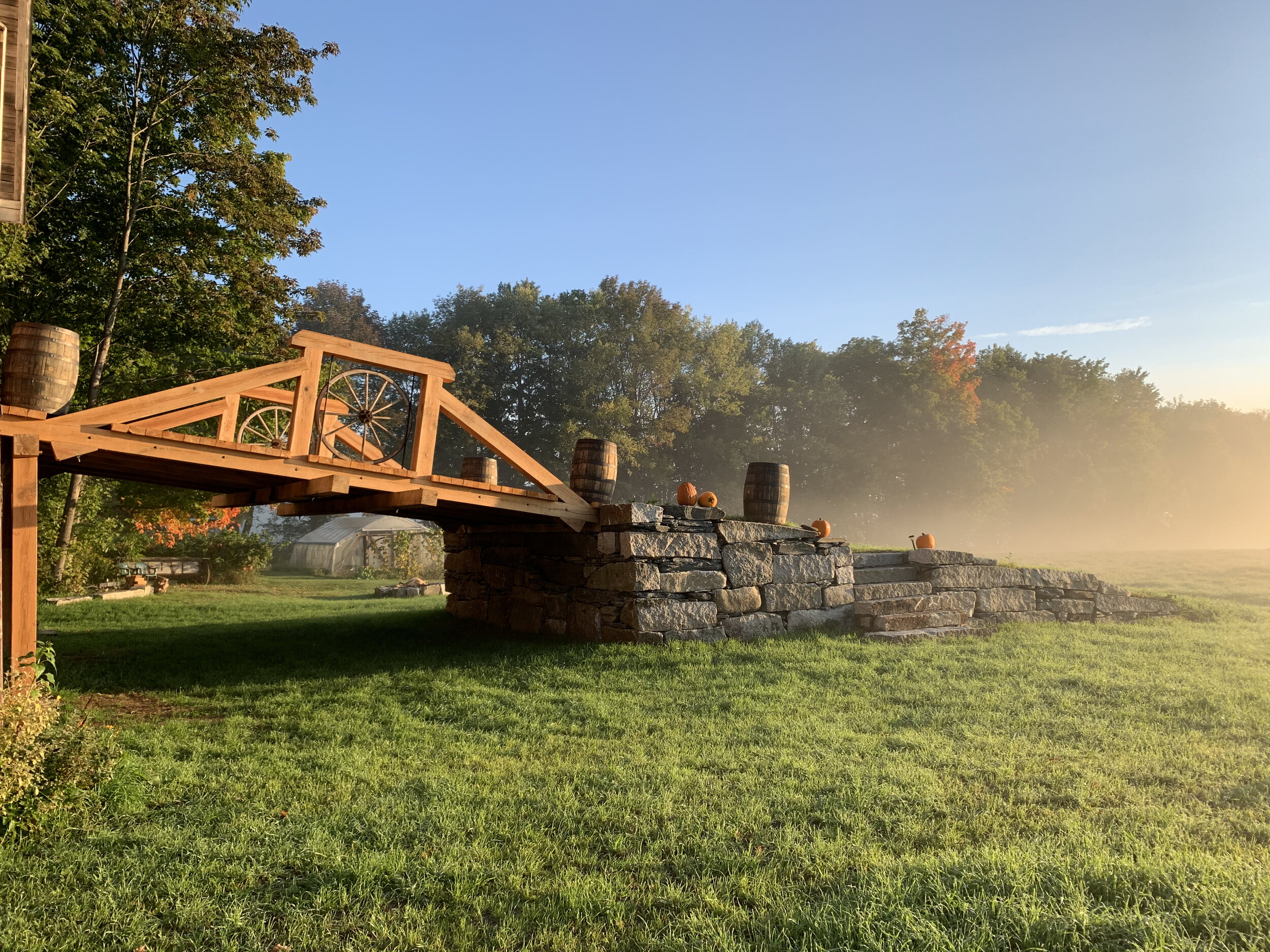 The bridge heading out of the barn to stone steps in a field covered in fog