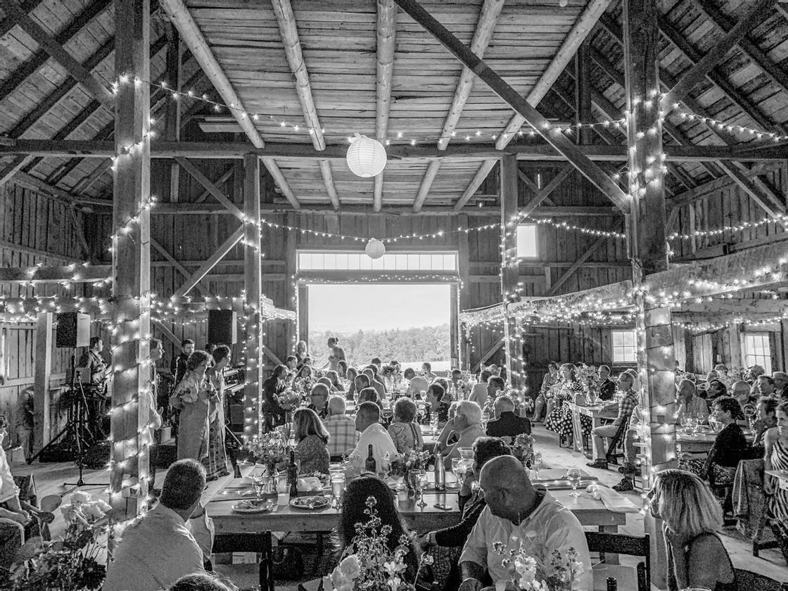 A black and white photo of wedding guests celebrating in a barn 