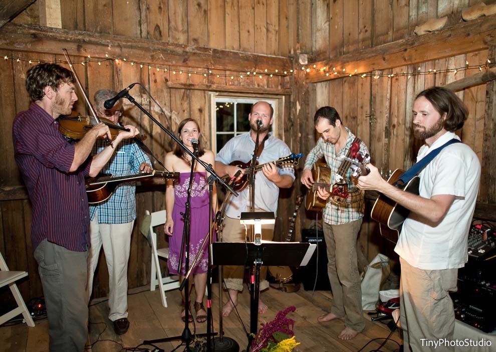 A bluegrass band playing in the corner of a lit barn