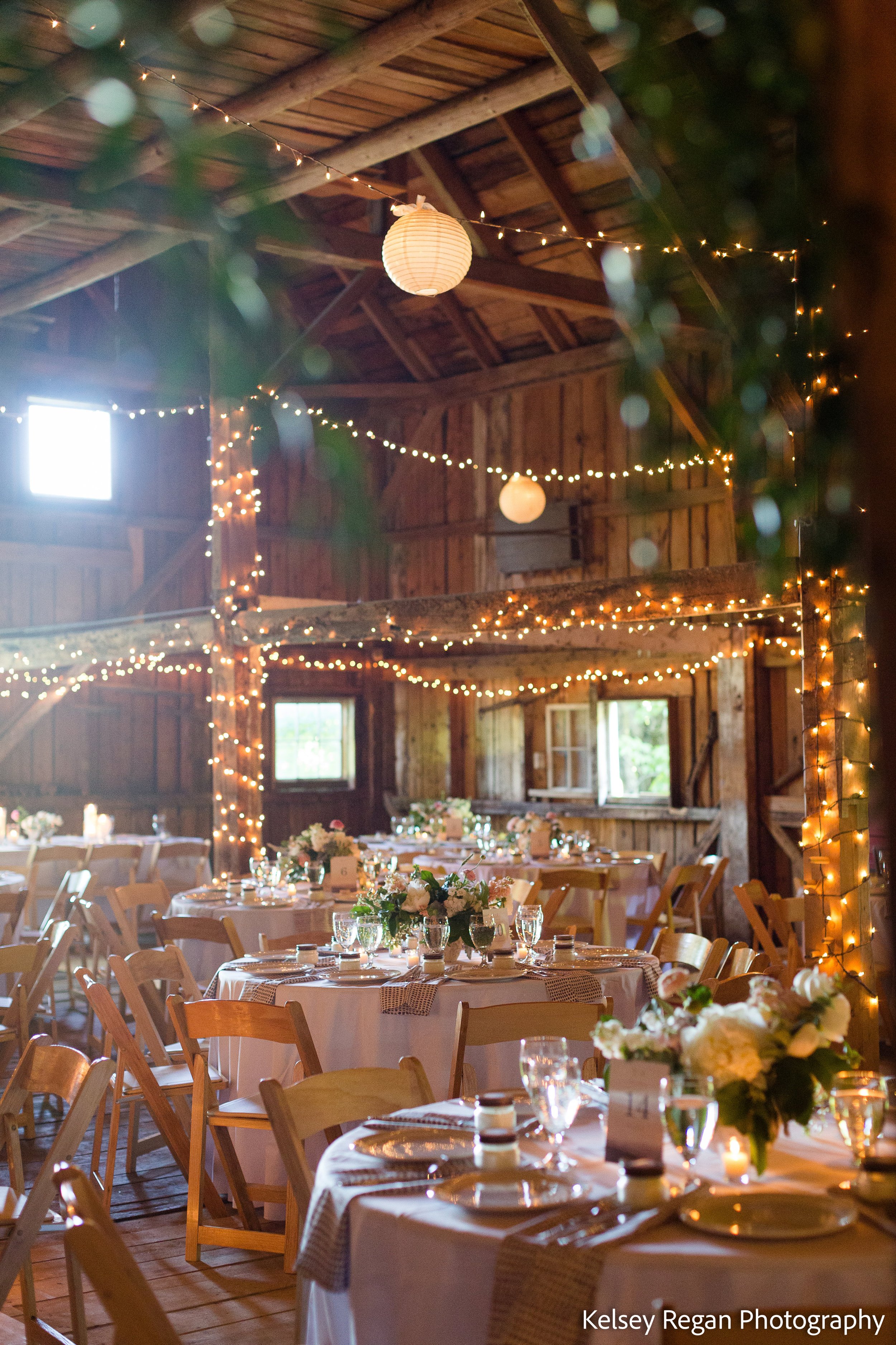 A barn lit up and filled with decorated tables set for a reception