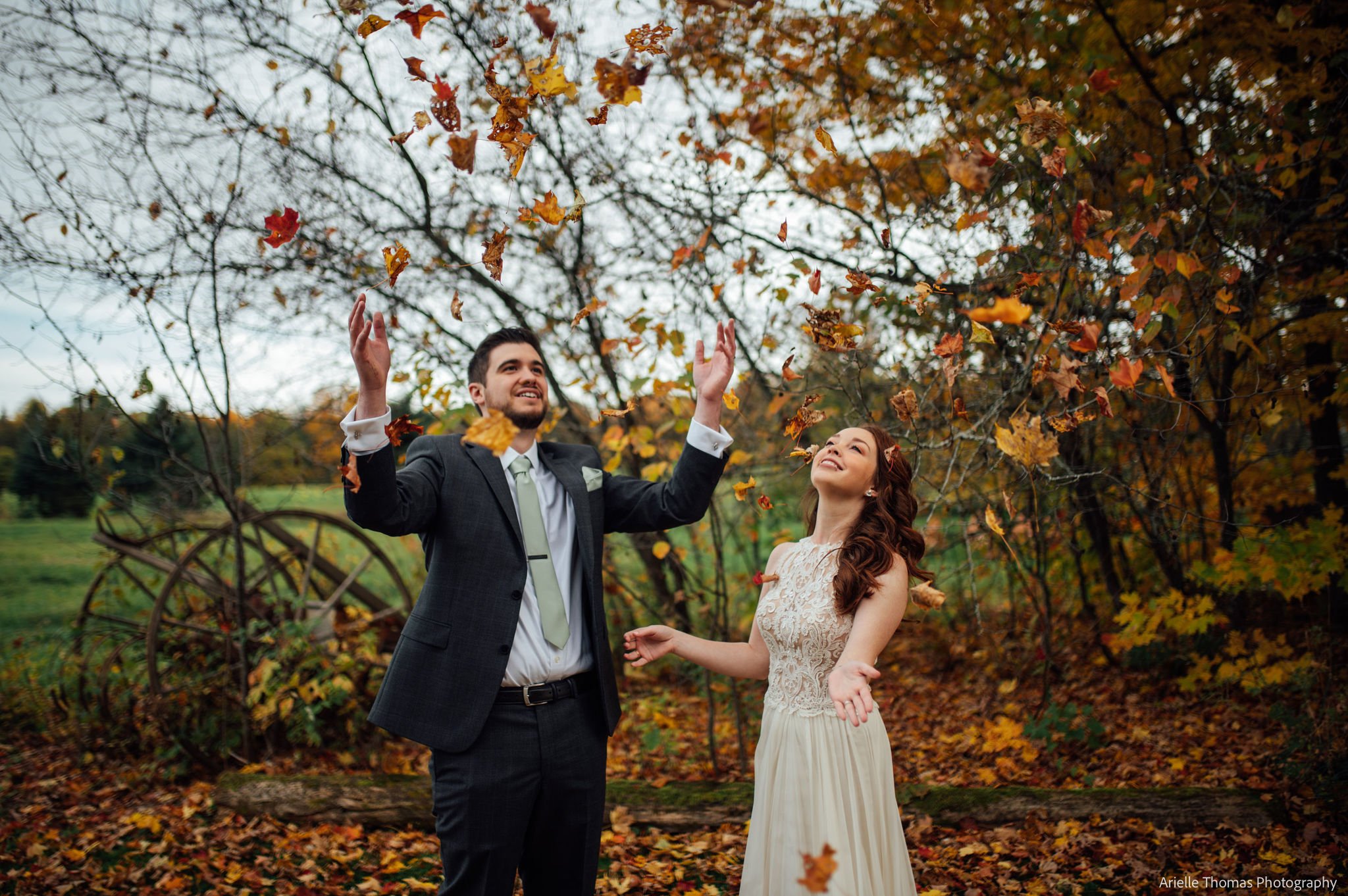 A bride and groom outside with fall leaves all around them