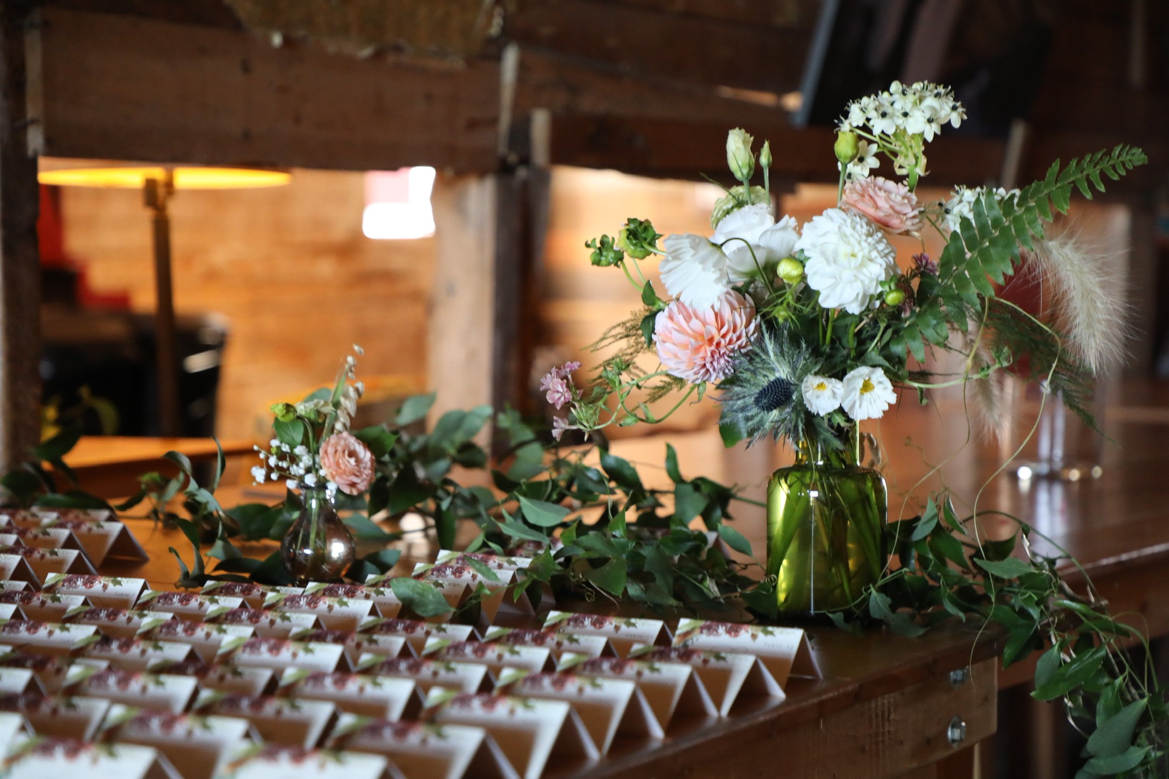 Table cards on a table with flowers inside of a barn