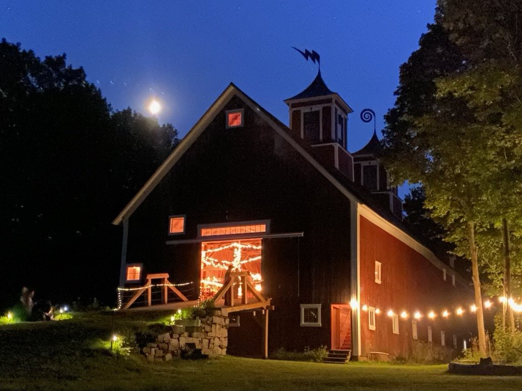 An outside view of a barn lit up and festive in the moonlight 