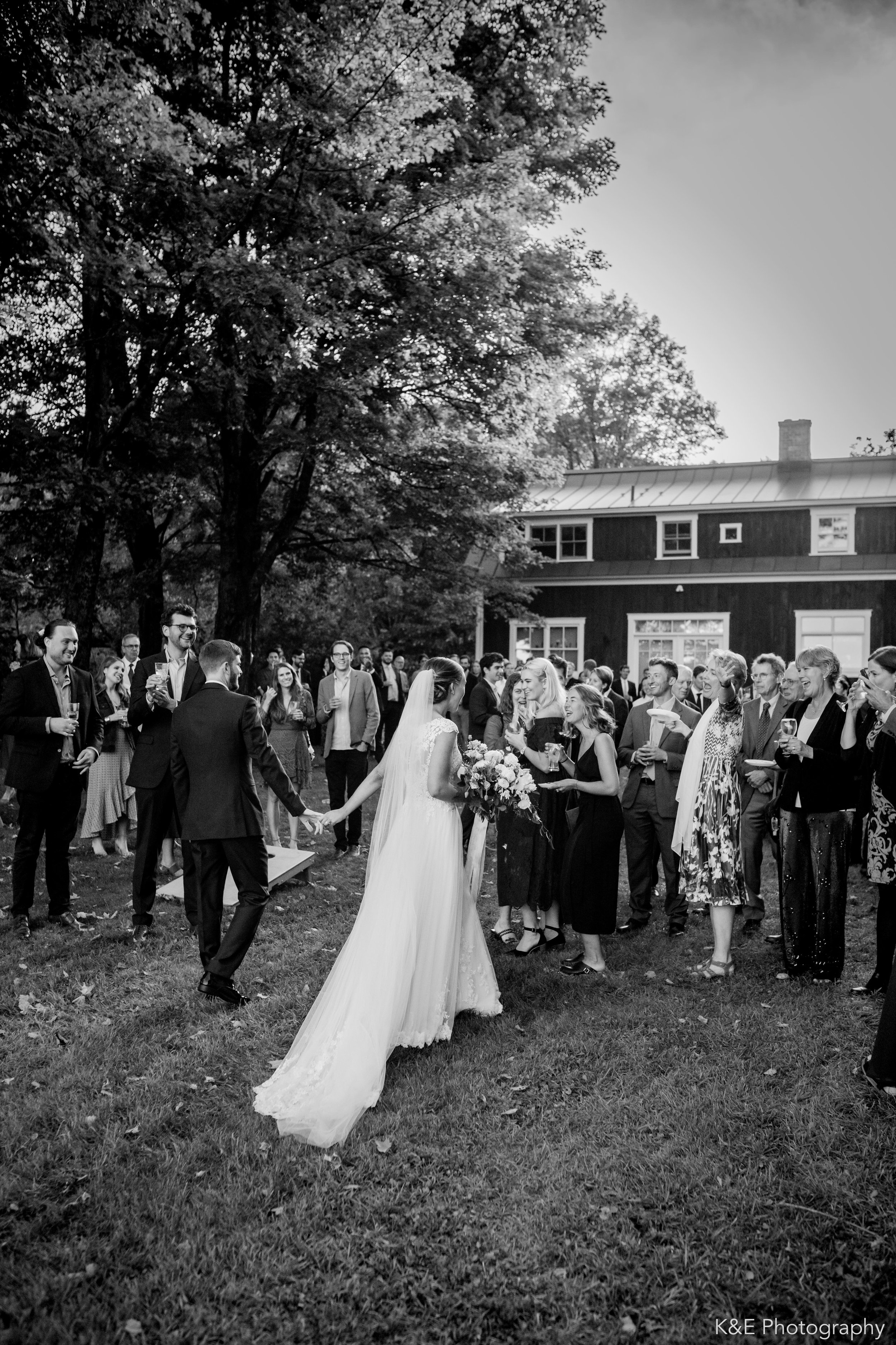 A bride and groom walking through their guests on the way to the barn