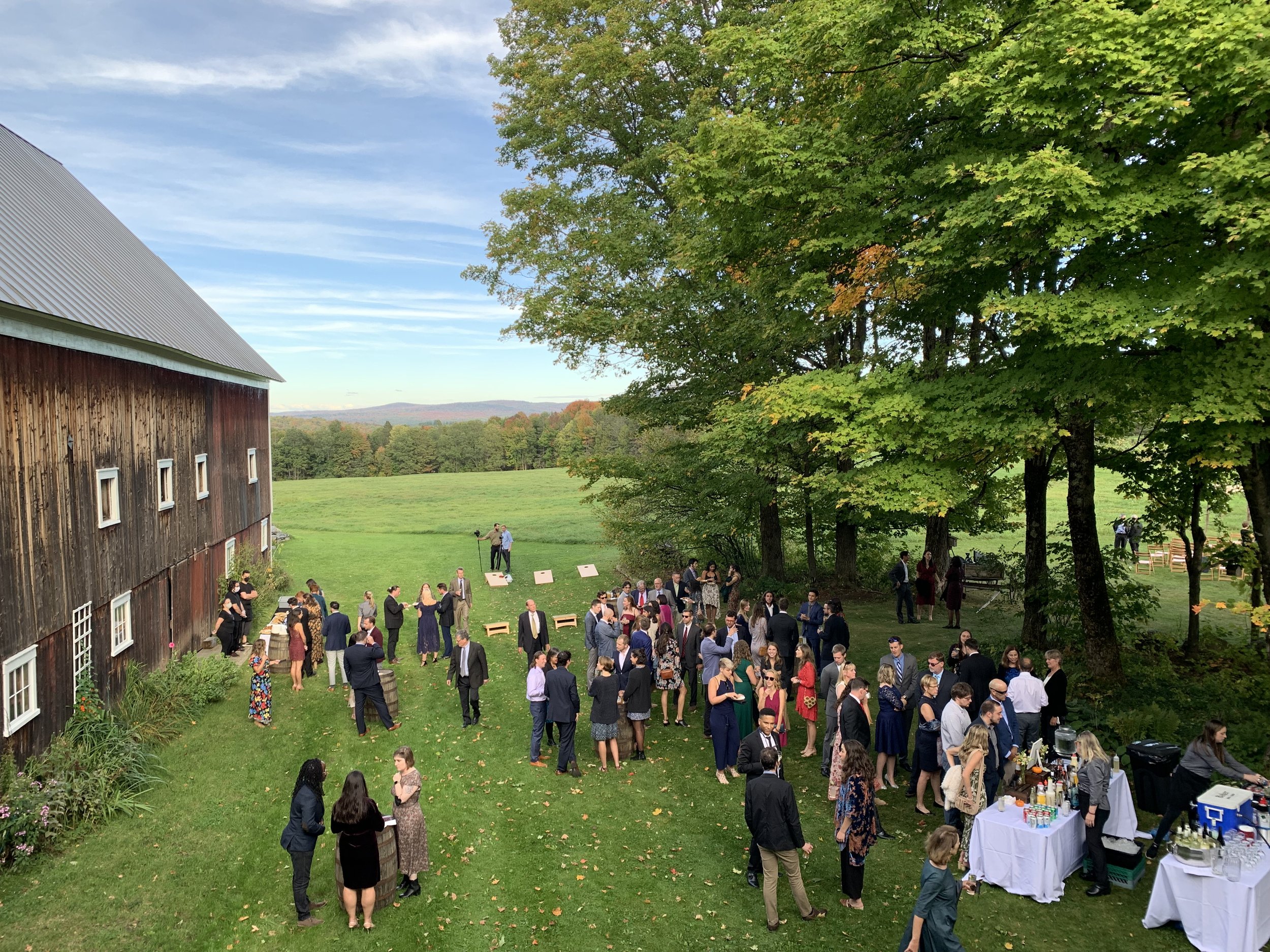 Wedding guests celebrating outside on a sunny day outside of a rustic barn