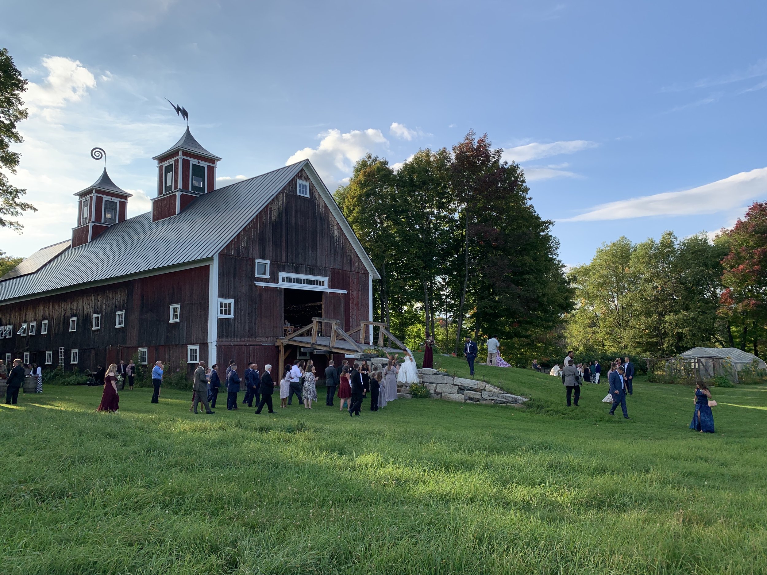 Bride and Groom and guests gathering outside of Turning Stone barn in Vermont