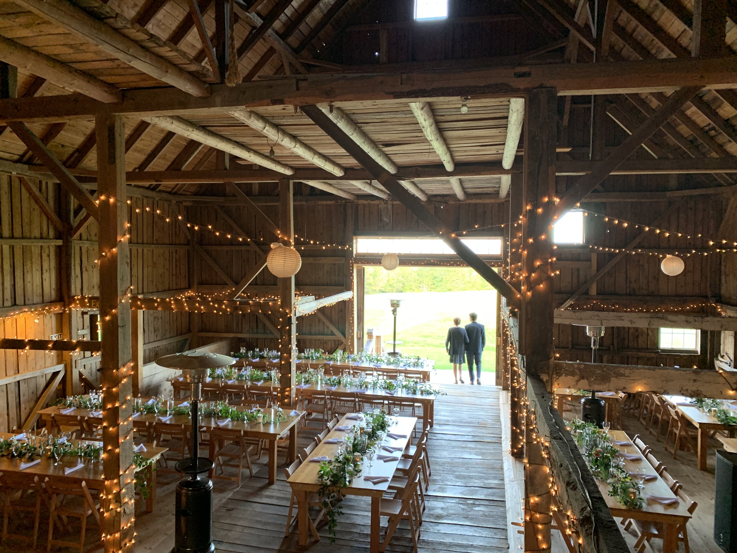 A view of a decorated barn ready for a wedding reception 