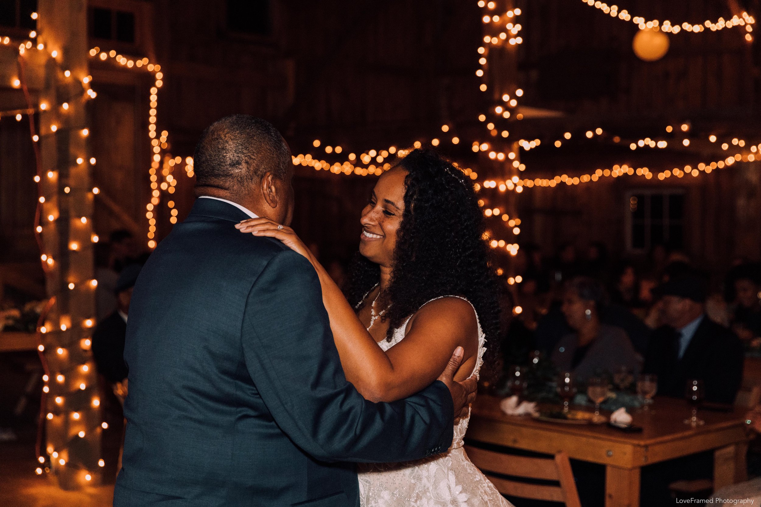 A bride dancing with her father in a dimly lit barn