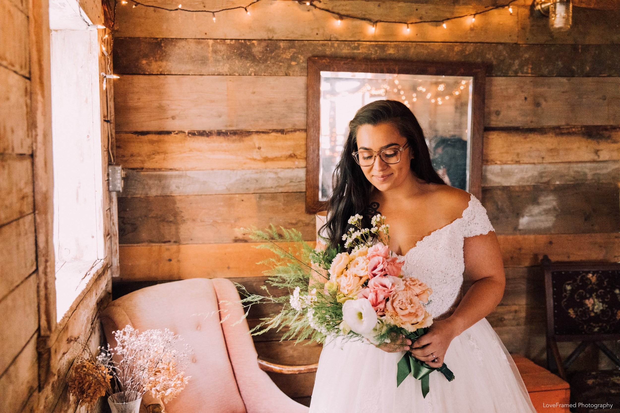 A bride and her bouquet in the corner of the barn