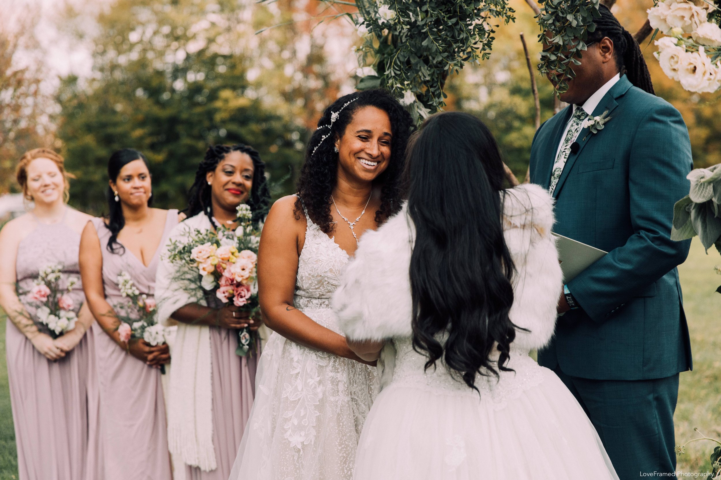 Two brides exchanging their vows surrounded by the officiant and bridesmaids