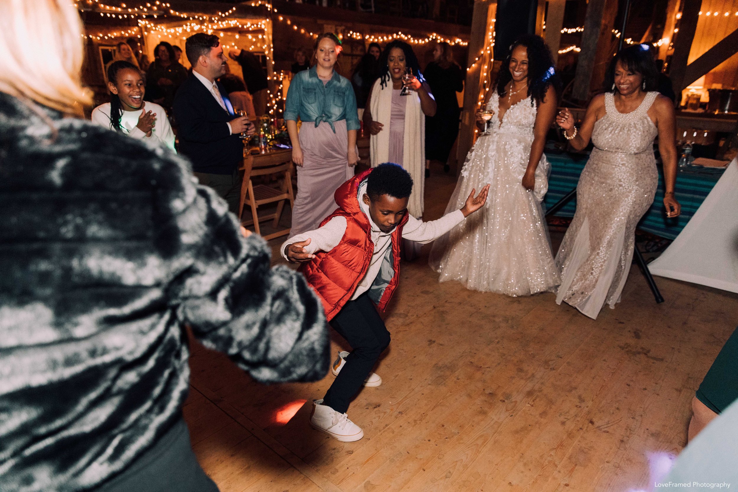 A wedding guest dancing within a circle inside a lit barn