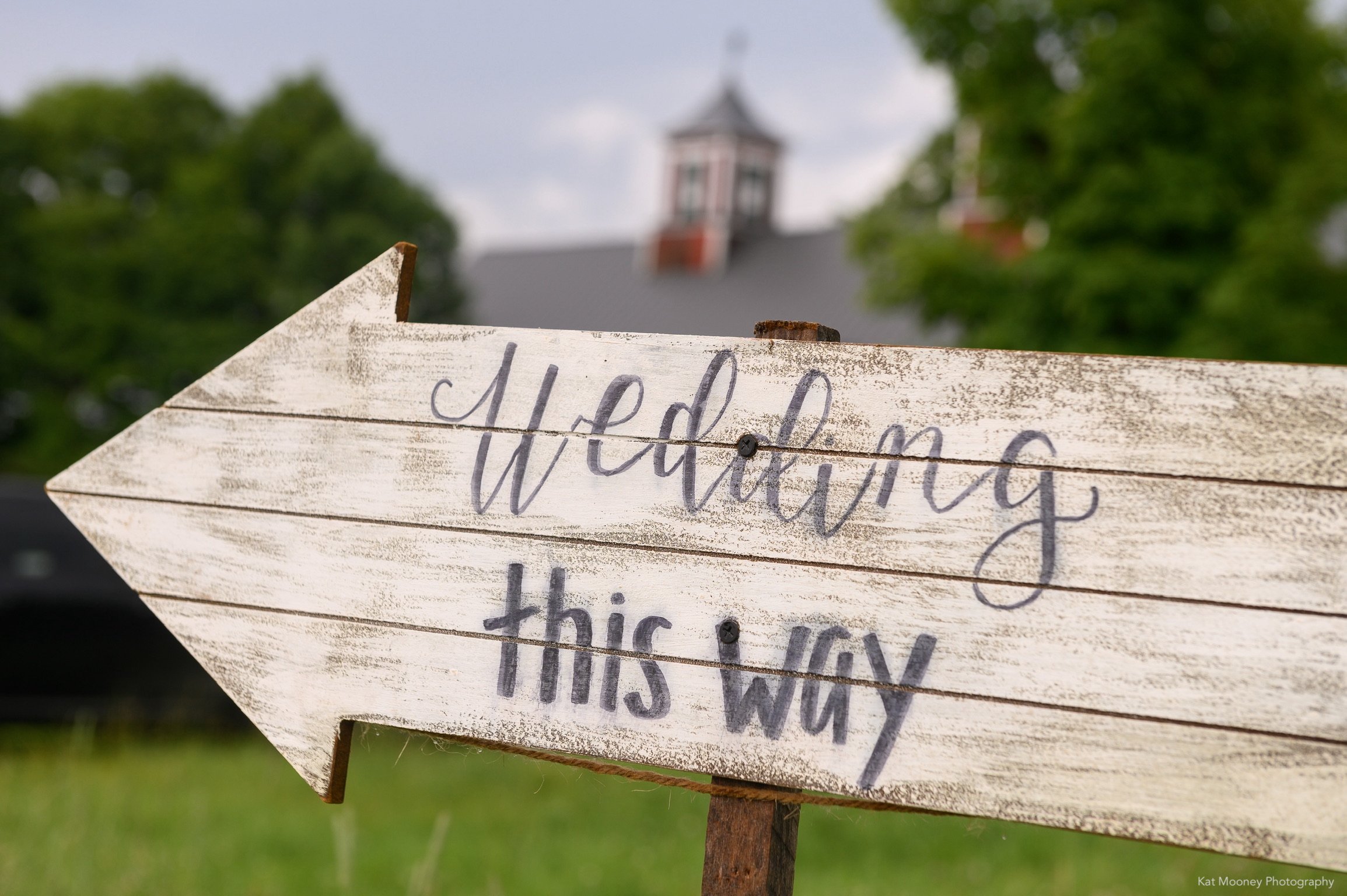 A wedding sign on reclaimed wood with the barn in the distance