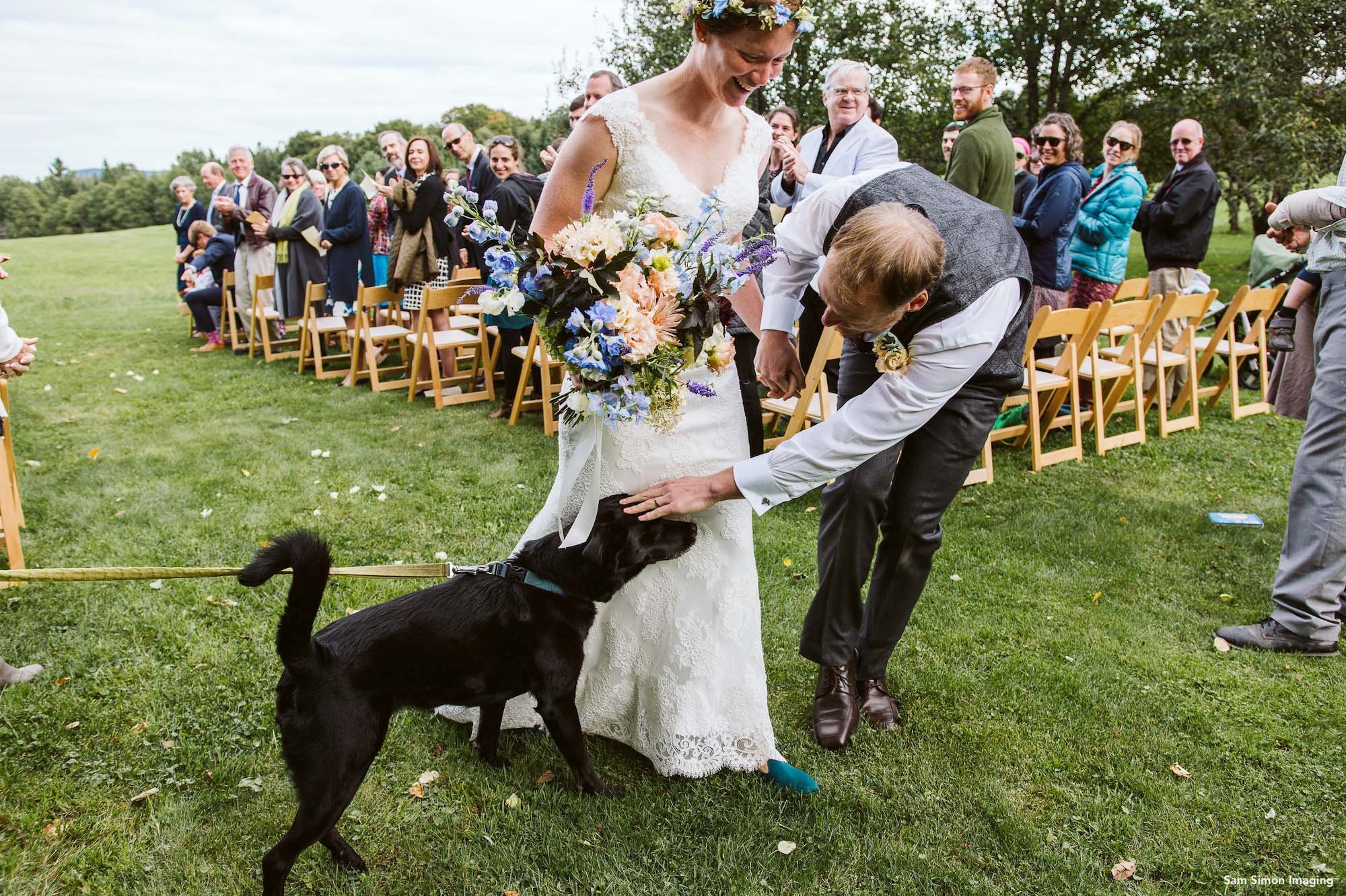A dog joins the bride and groom at an outdoor wedding