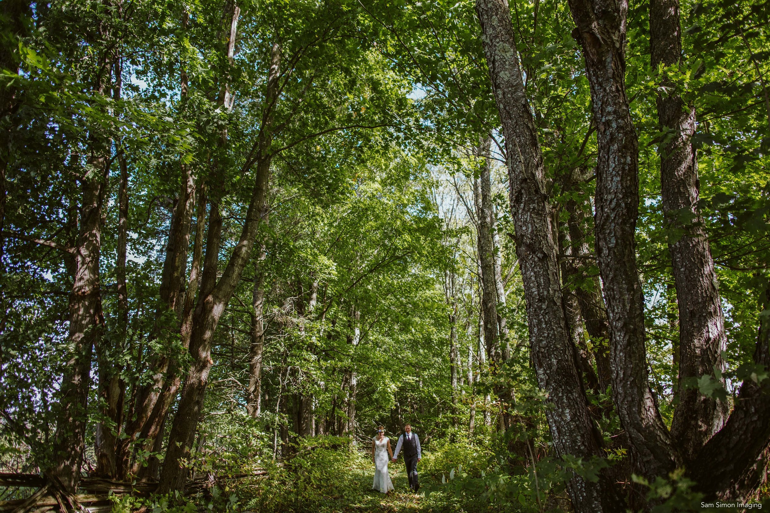 A bride and groom walking in the woods in northern Vermont