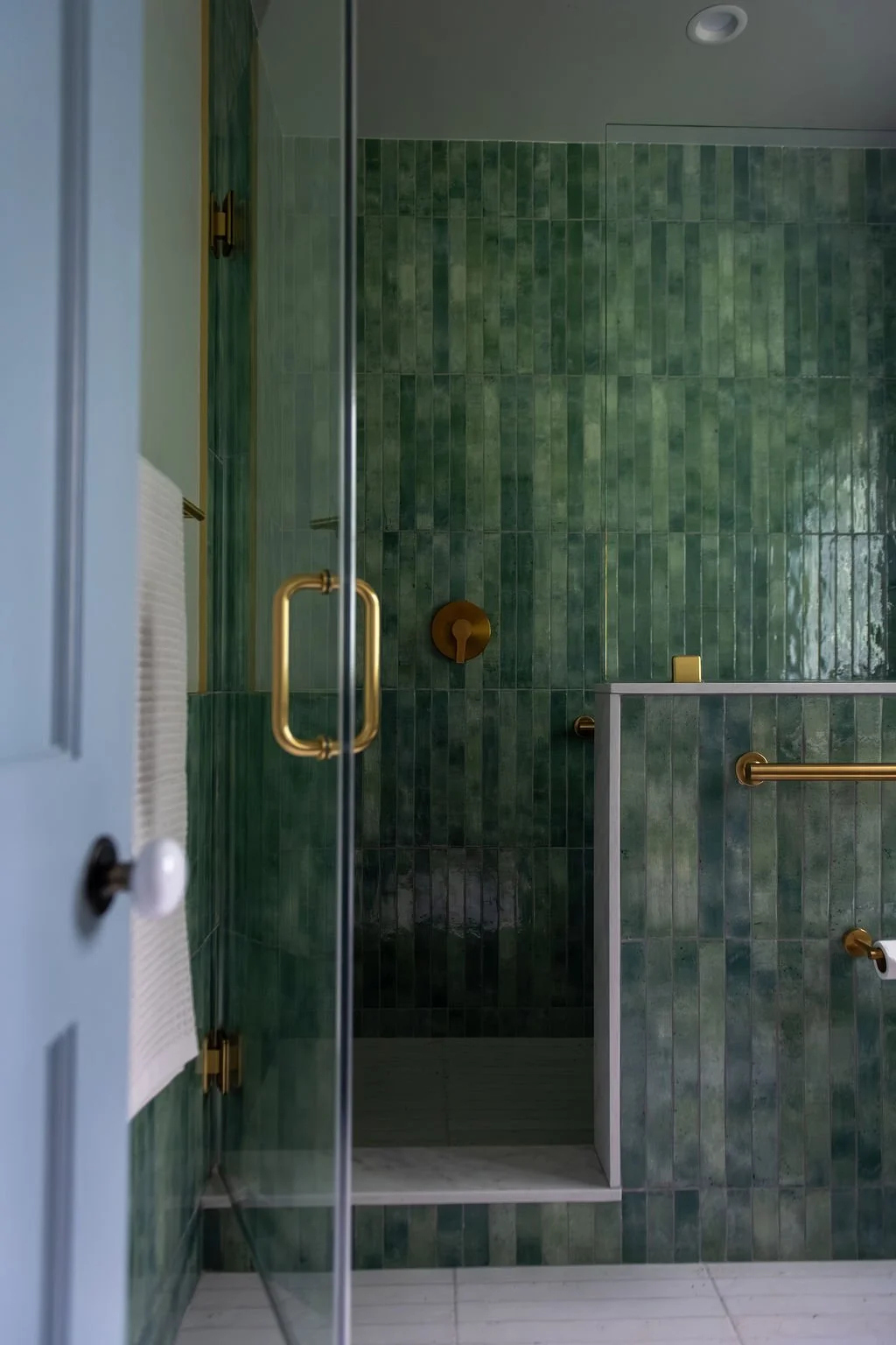  Where the old kitchen once stood, the family now has a spa-like shower with the controls set just inside the glass door, so the water can be turned on and warmed up before anyone steps in. It's a small detail with brass accents that makes a daily ro