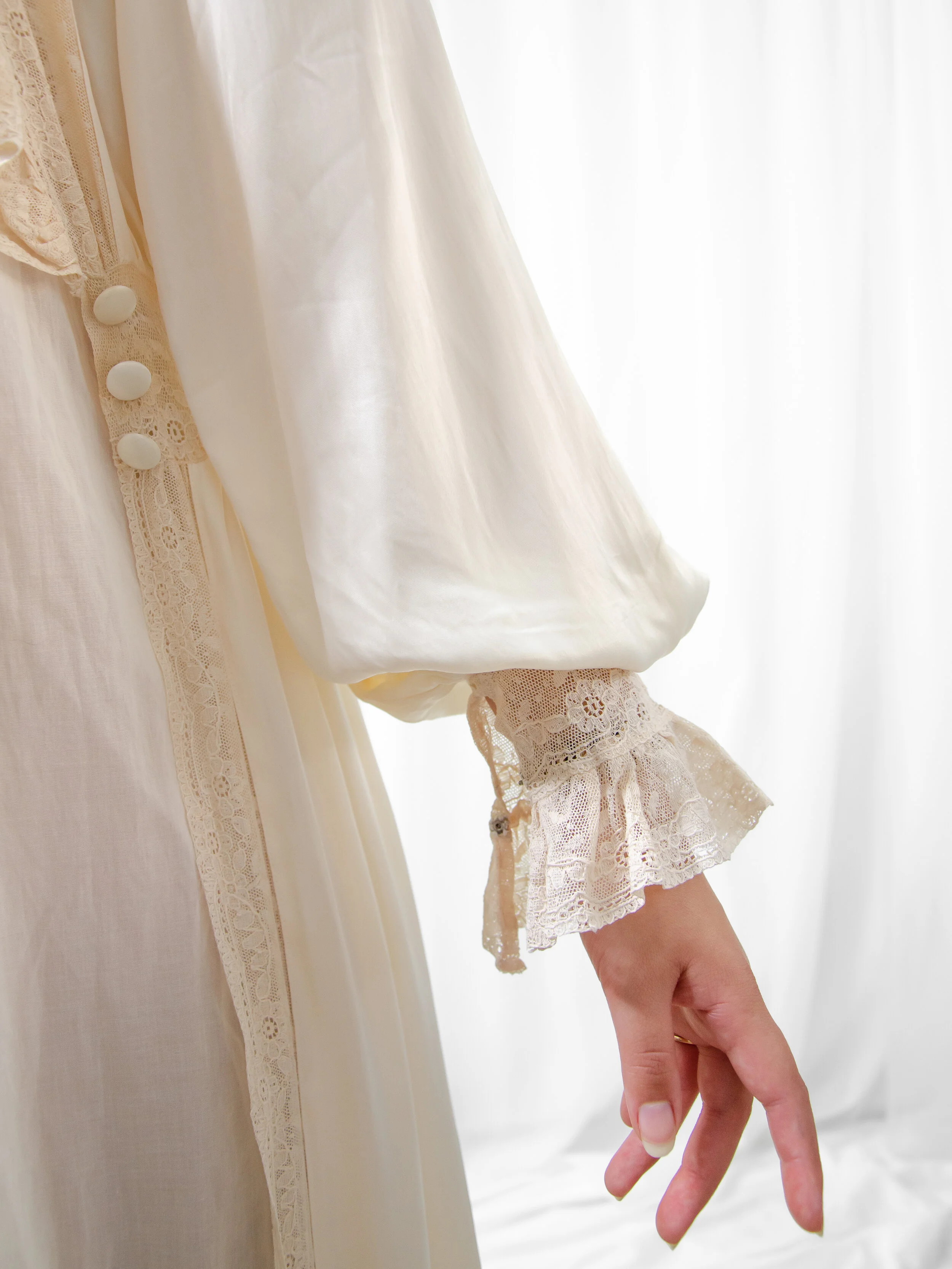 Detail of the 1940s satin bridal robe's puff sleeve with ruffled lace cuff and covered front buttons.