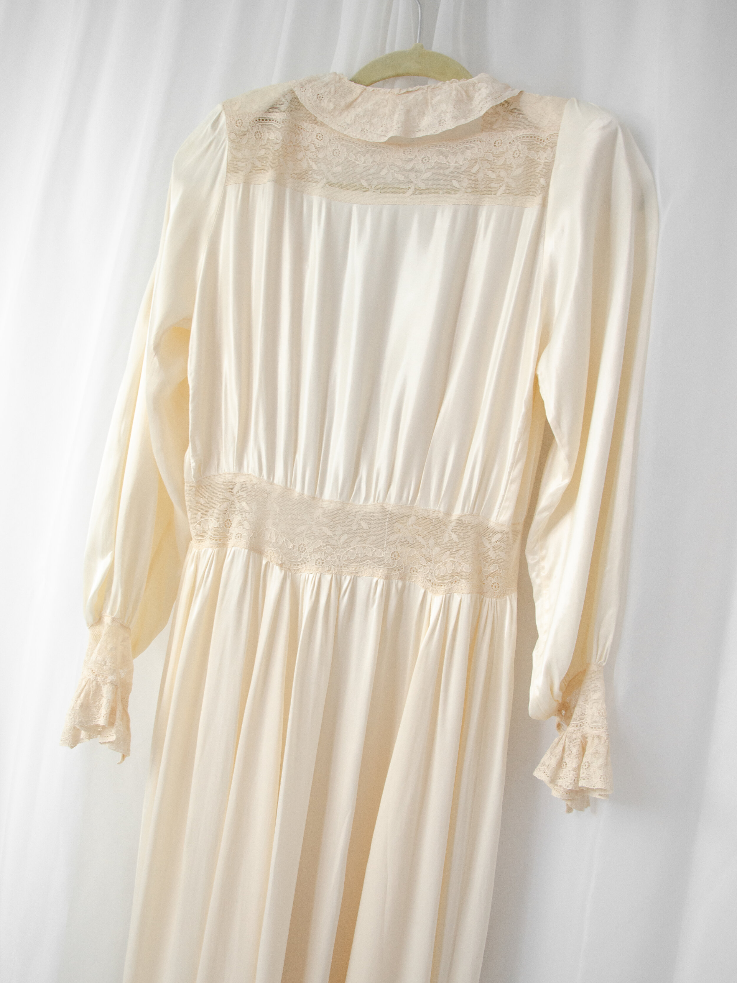 Back view of the 1940s satin bridal robe on a hanger, showing the lace yoke and lace waist panel.