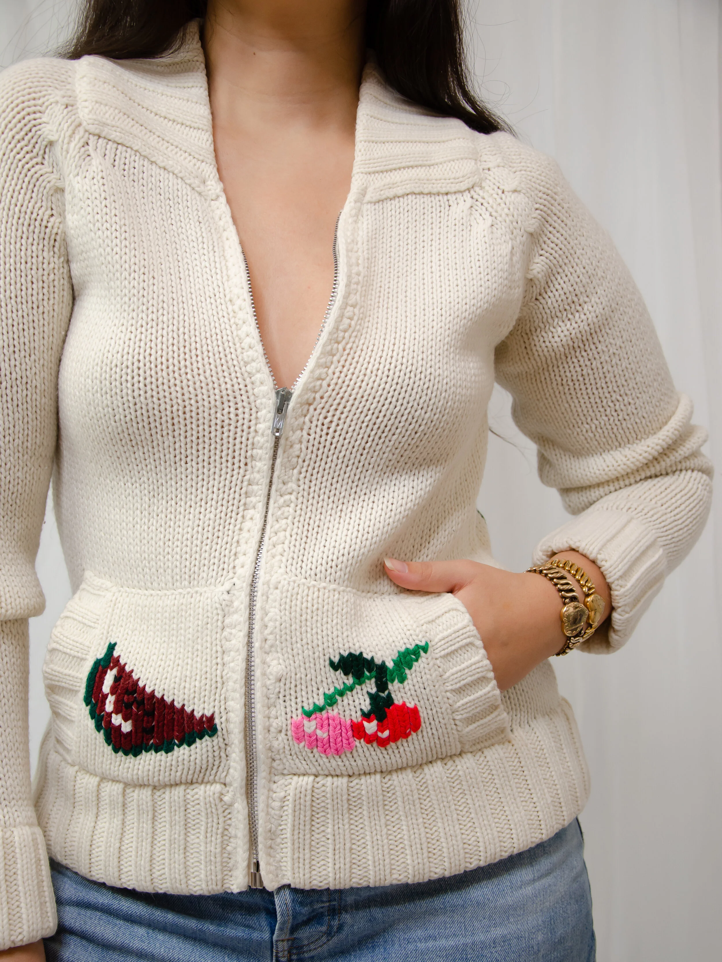 1970s cream knit zip-front cardigan on a model, showing watermelon and cherry knit pockets.