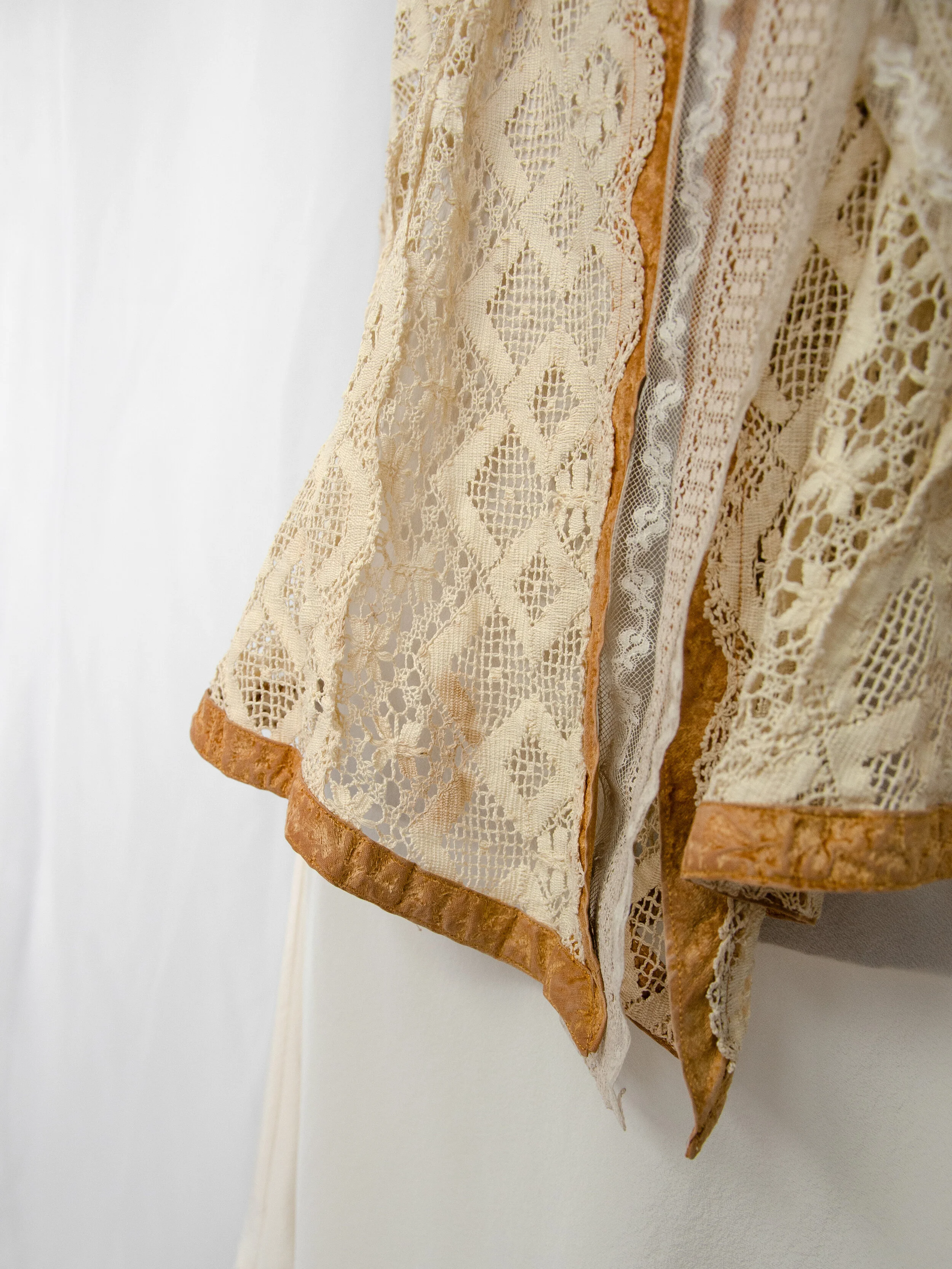 Detail of the Edwardian lace jacket's open front edge, showing the diamond-pattern lace and velvet trim.