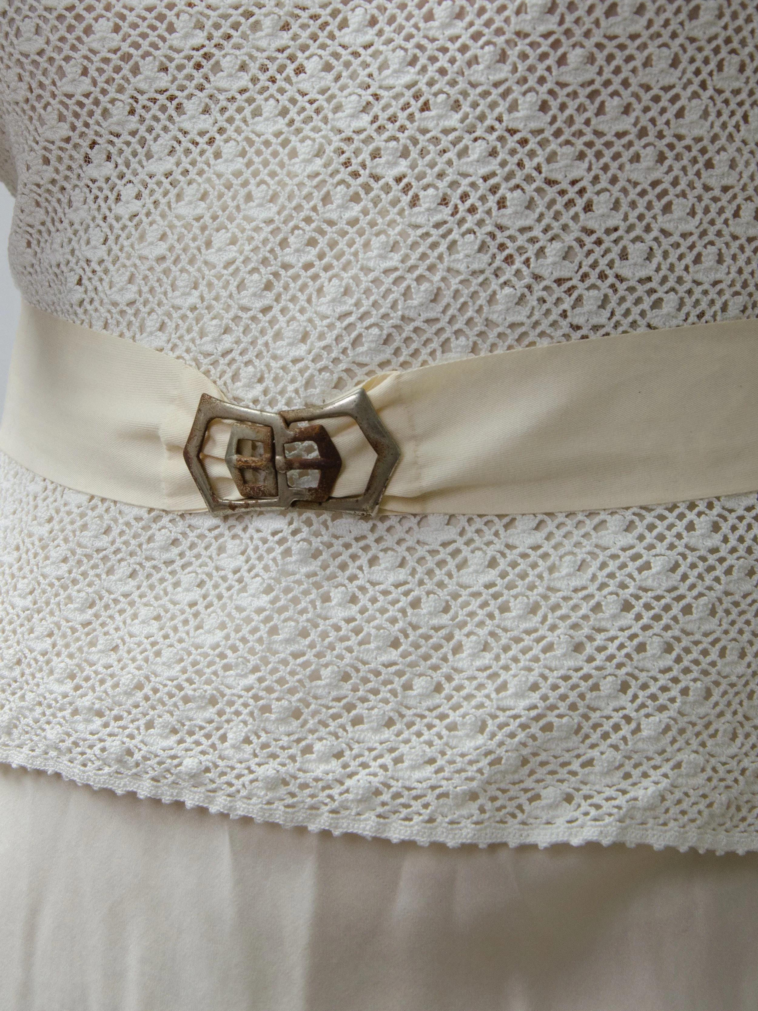 Close-up of the 1940s ecru ribbon belt cinched over a crochet lace top, showing the metal buckle.