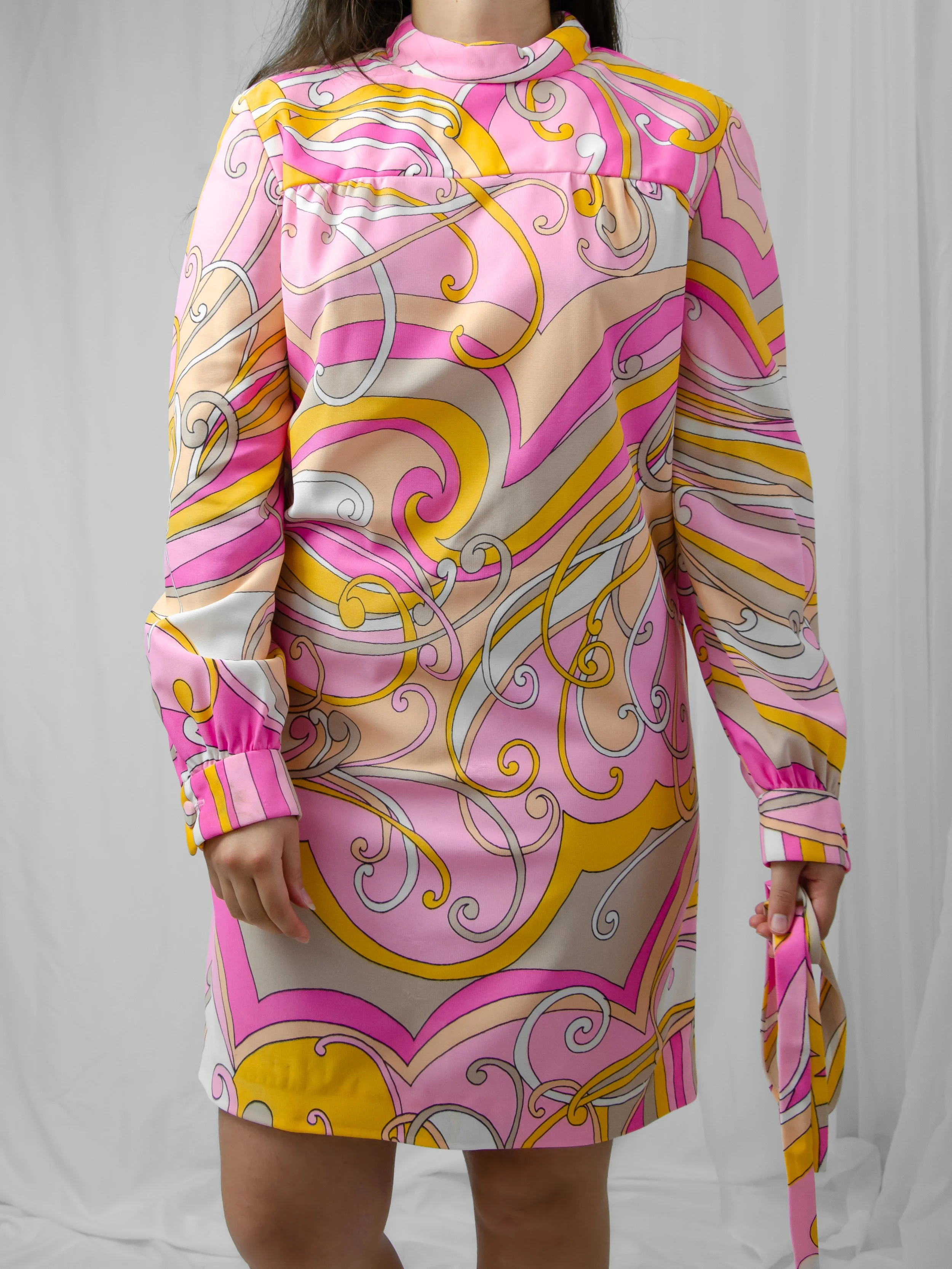 1960s psychedelic swirl dress worn without the tie on a model holding the removable sash.