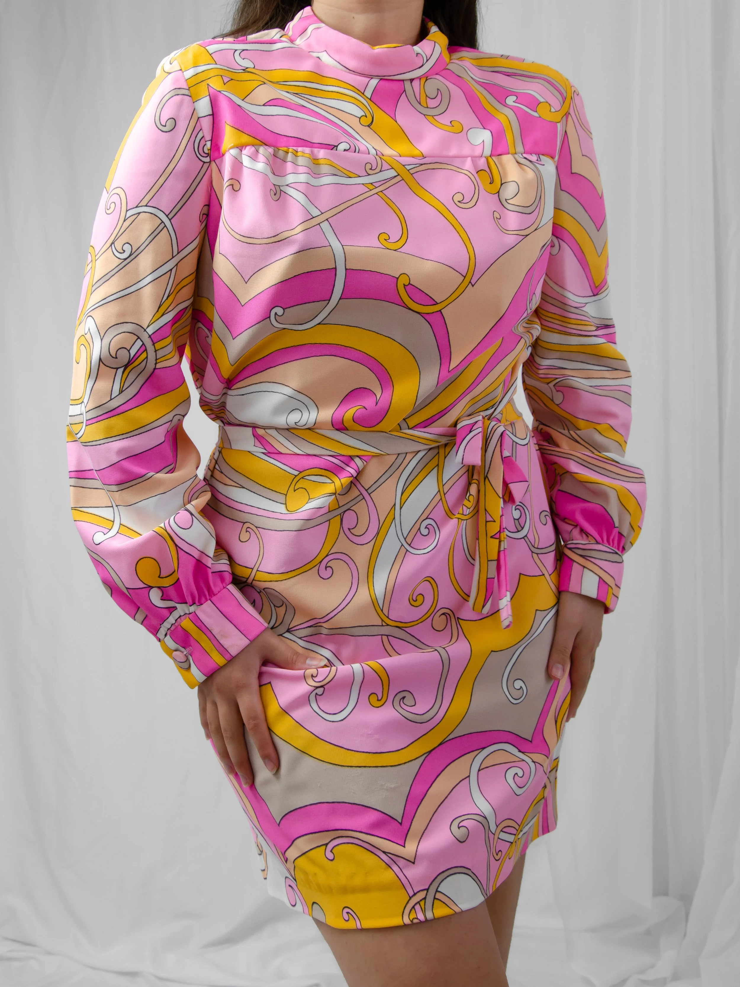 Front view of the 1960s Pucci-inspired pink and yellow swirl dress on a model, belted at the waist.