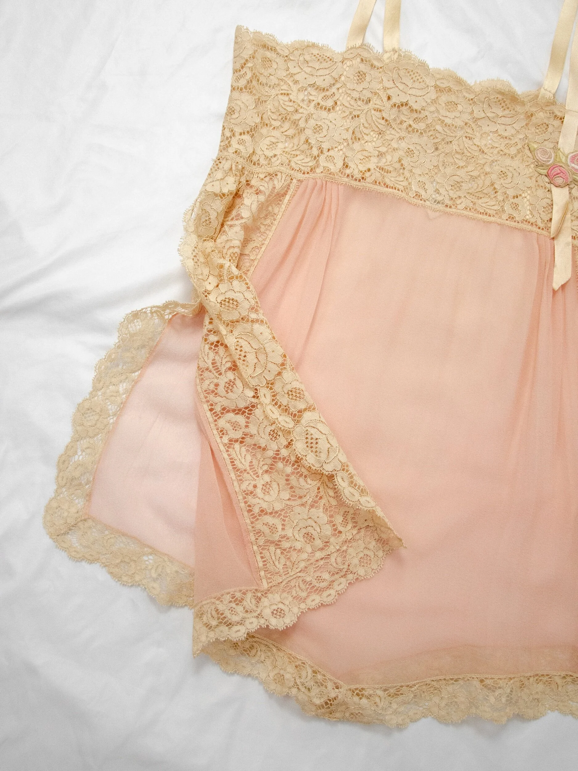 Detail of the 1920s silk teddy laid flat with one side folded, showing the lace side vent at the hip.
