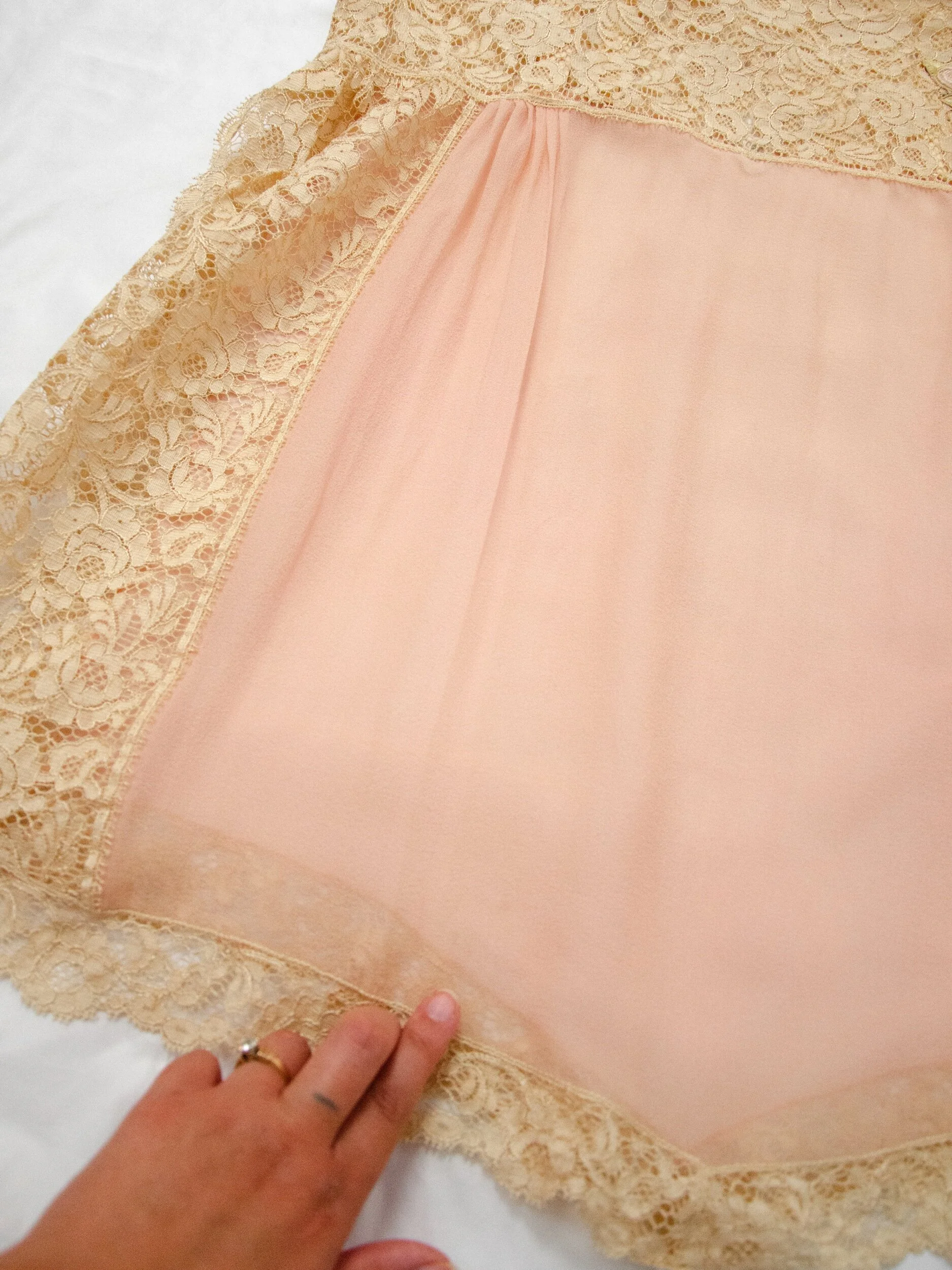 Detail of the 1920s silk teddy's front hip, a finger pointing to two faint small spots.