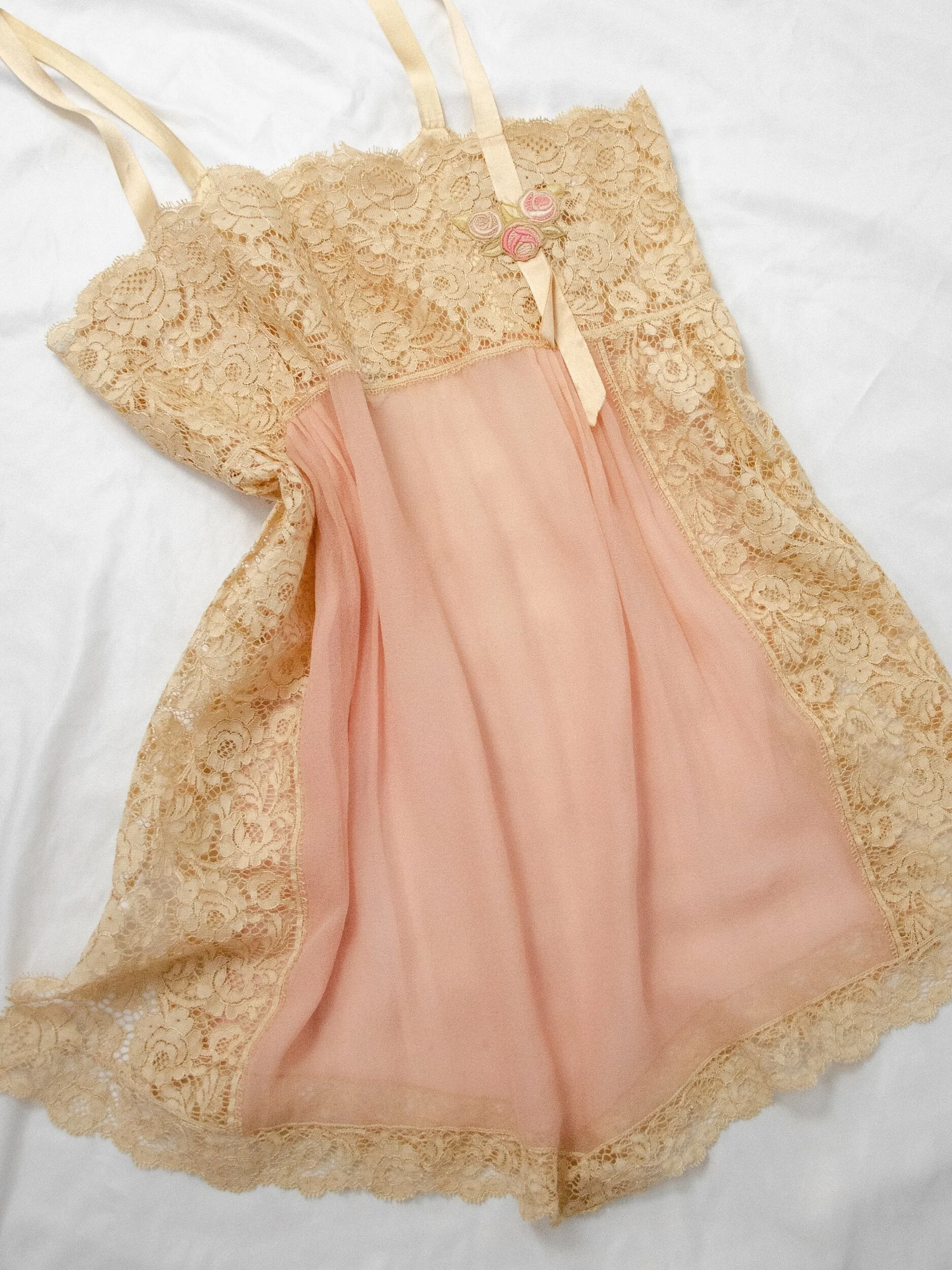 1920s dusty rose silk and lace teddy laid flat at an angle, showing the floral ecru lace panels.