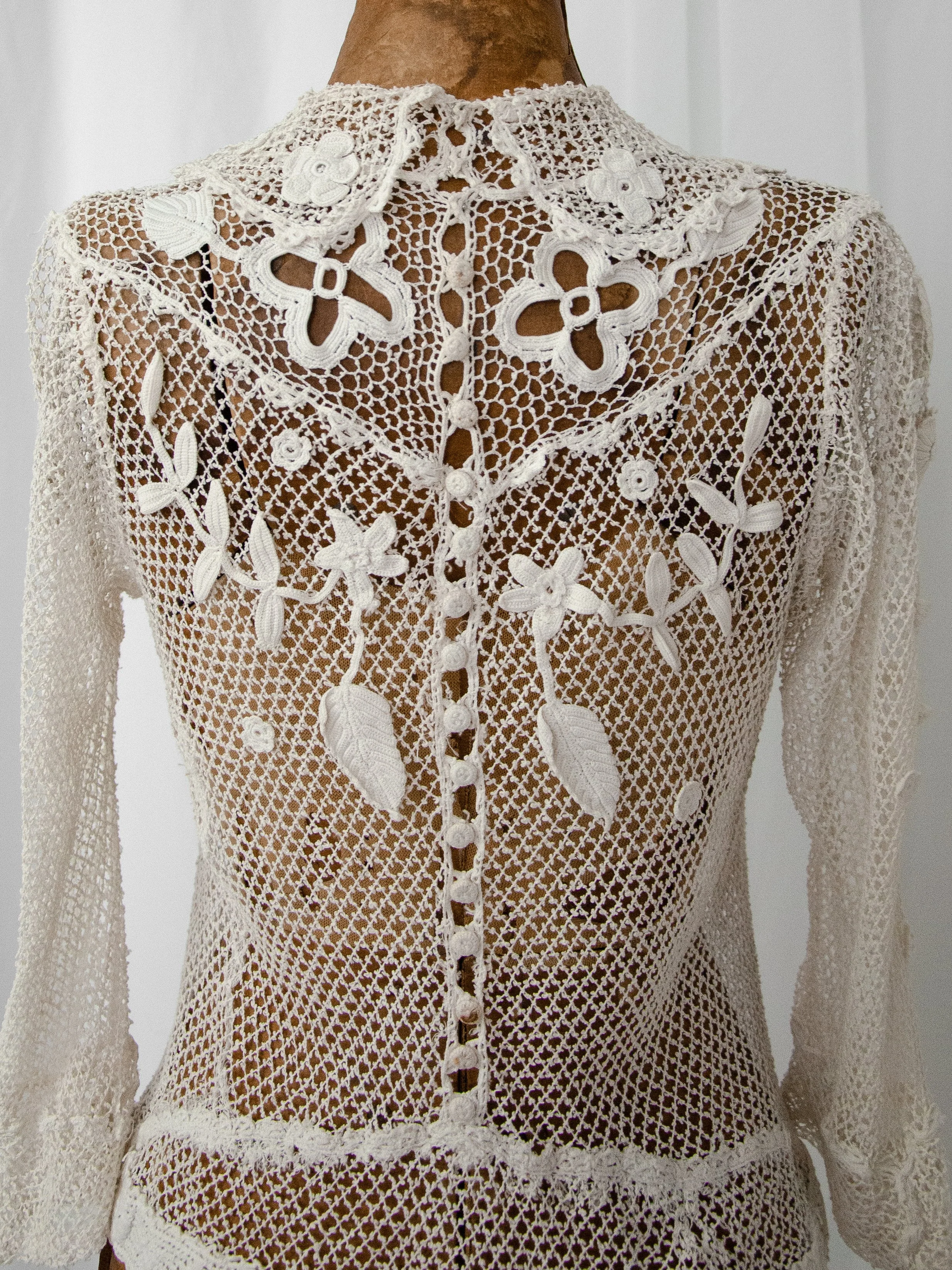 Back view of the antique Irish crochet top on a dress form, showing the crochet buttons and floral motifs.