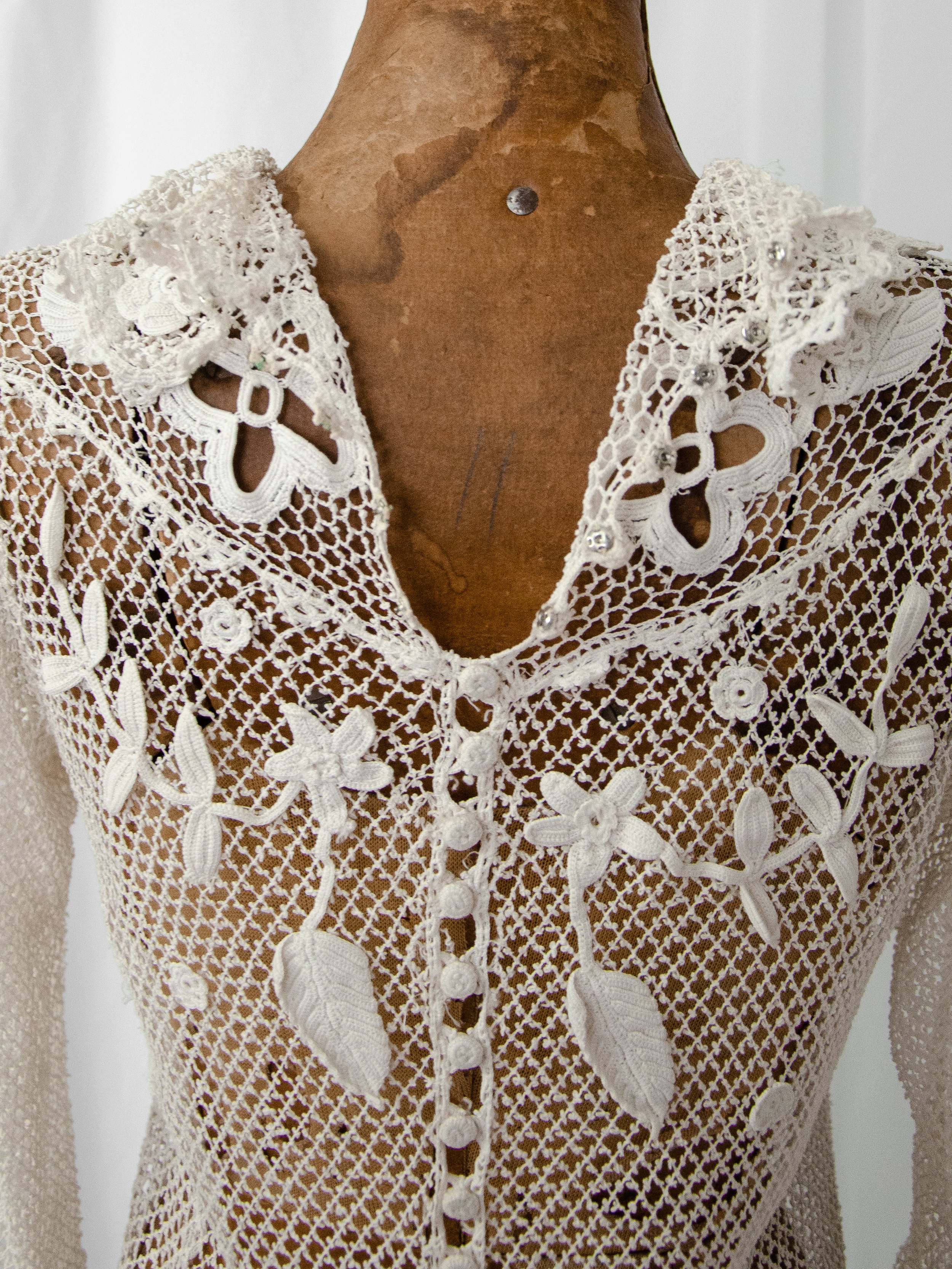 Close-up of the antique Irish crochet top's back neckline, showing raised floral appliqués and buttons.