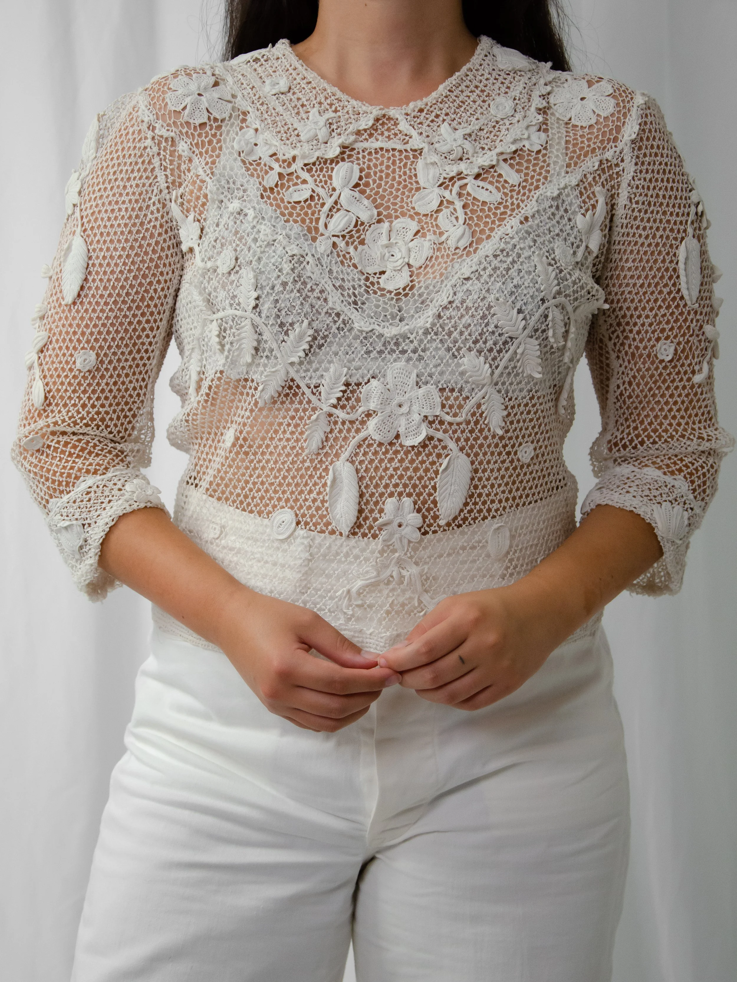 Antique warm white Irish crochet top with three-quarter sleeves, worn on a model with white trousers.