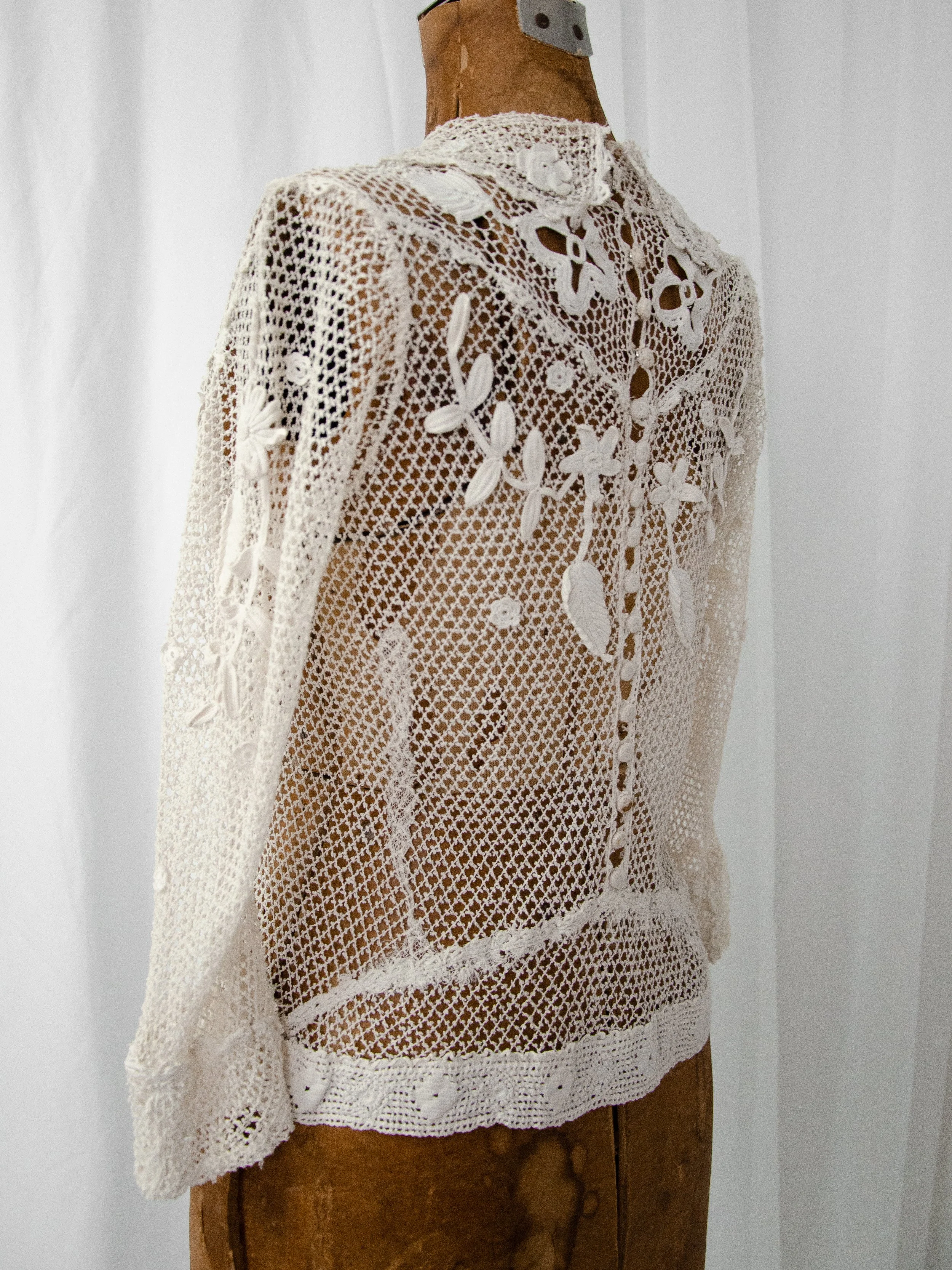 Three-quarter back view of the antique Irish crochet top on a dress form, showing the back buttons.