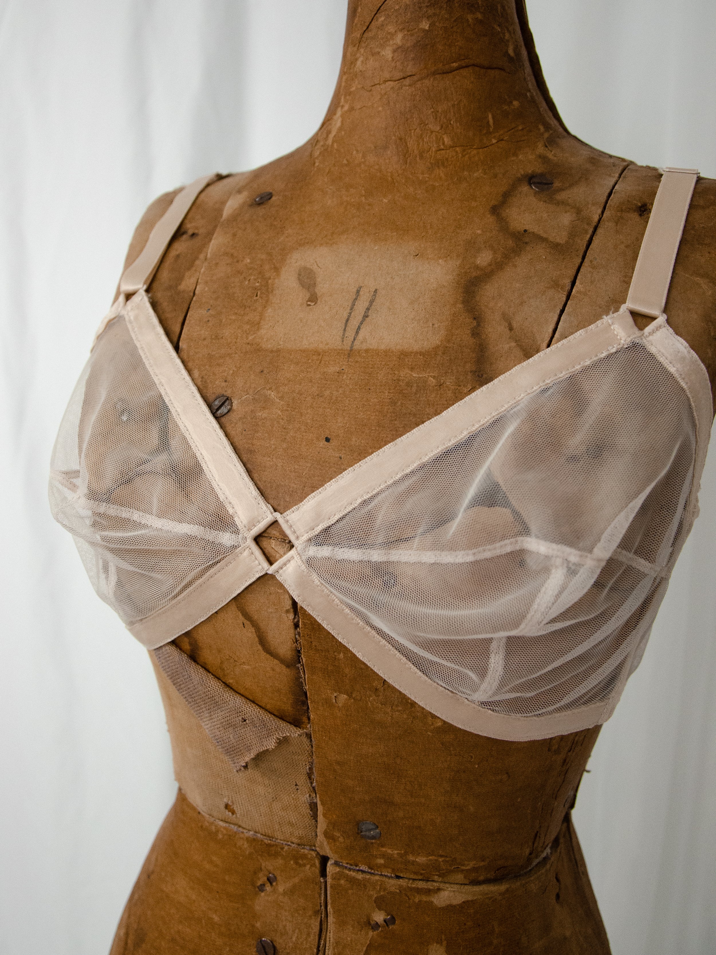 Close-up of the late 1940s Maidenform mesh bra on a dress form, showing the diamond keyhole center.