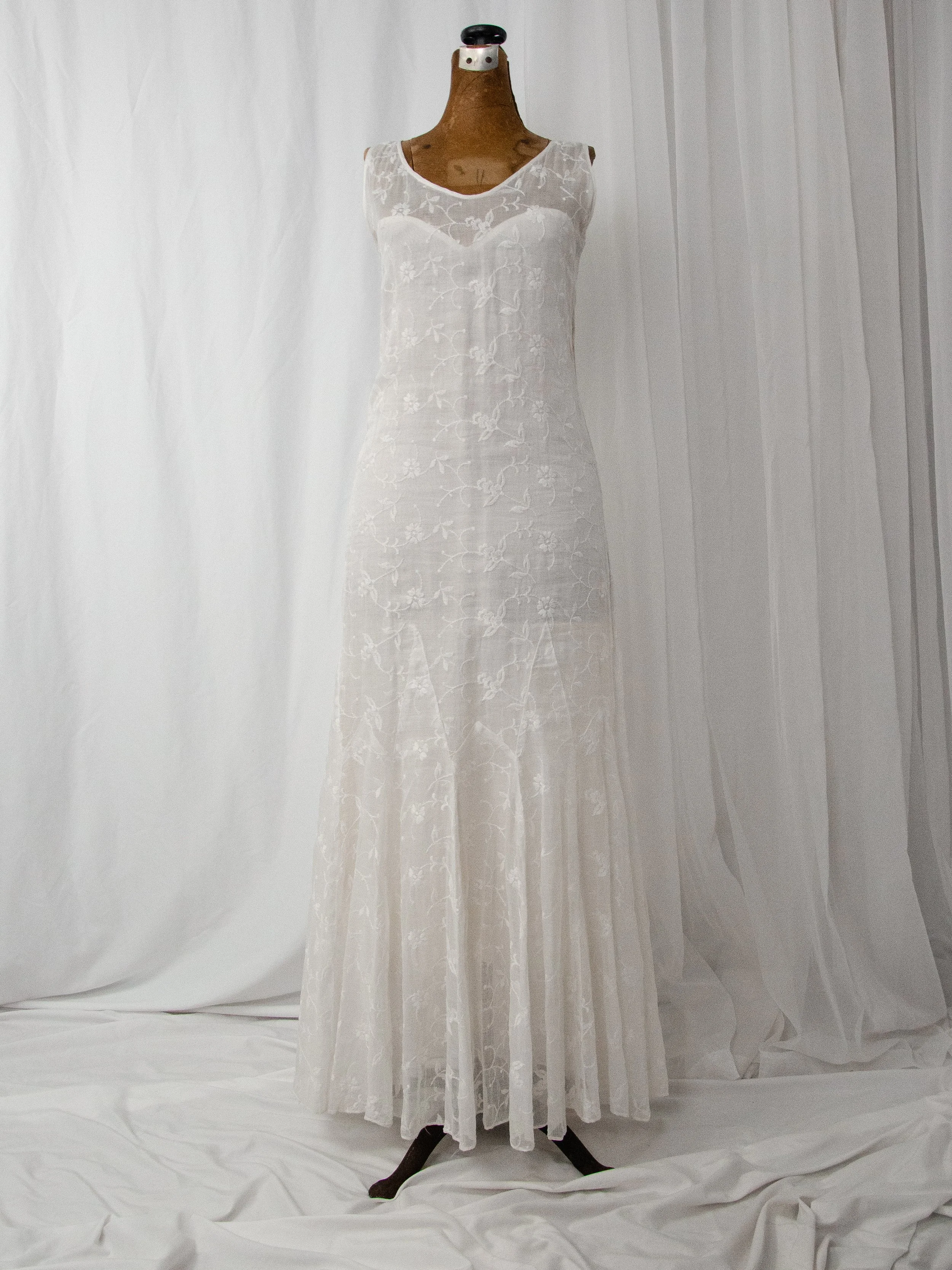 1930s white cotton organdy dress with floral embroidery on a dress form, full-length front view.