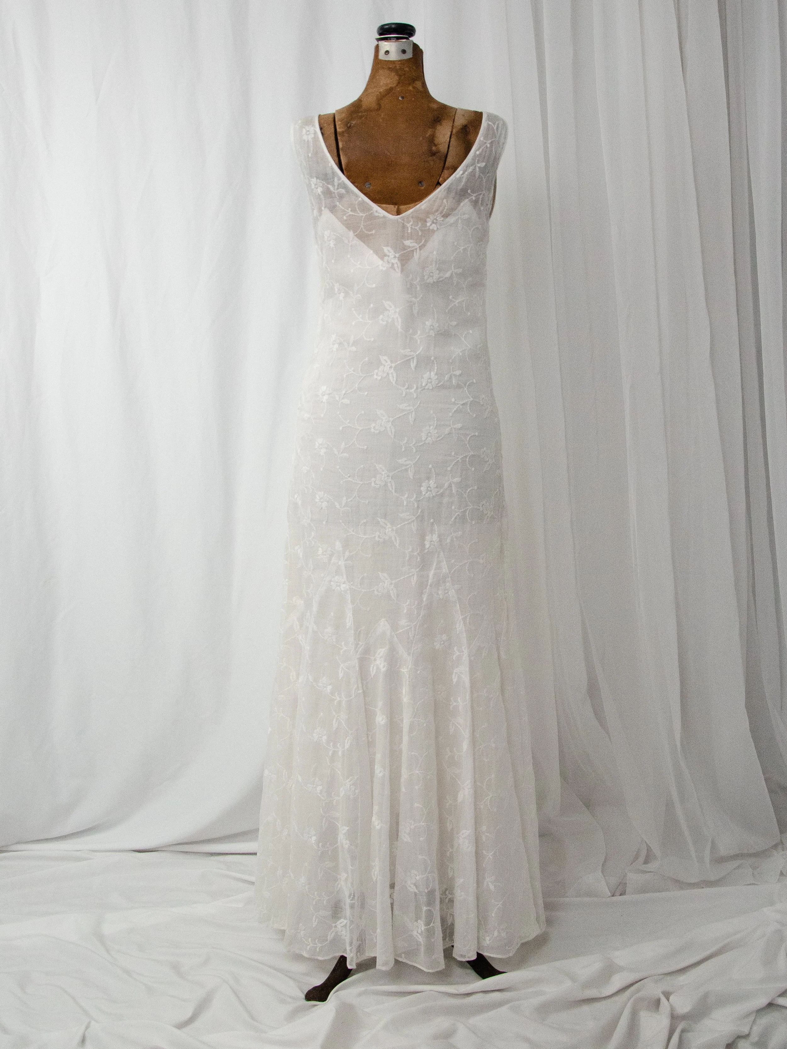 Back view of the 1930s white embroidered organdy dress on a dress form, showing the V-back.