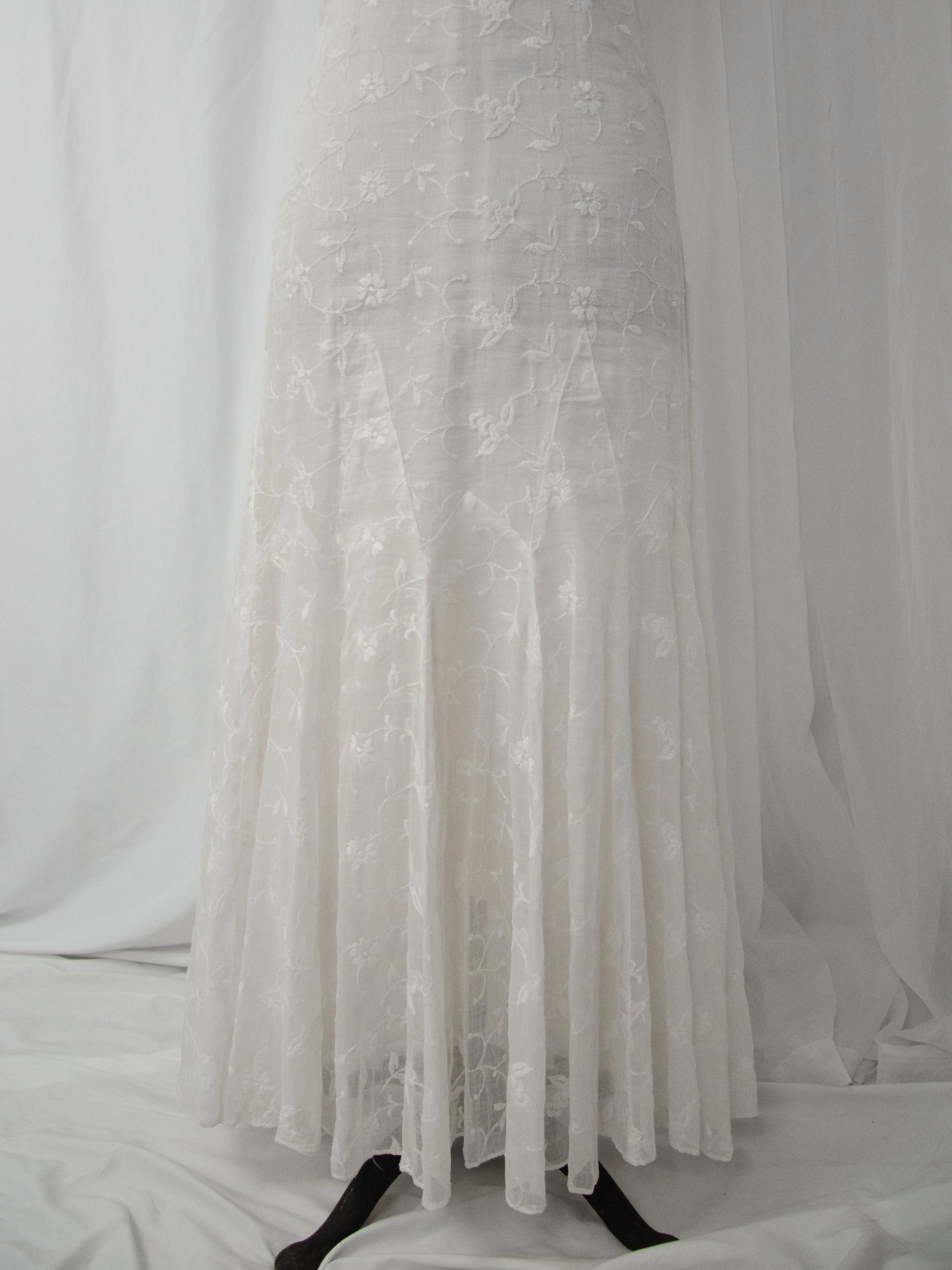 Detail of the 1930s white organdy dress skirt, showing flared godet panels and floral embroidery.
