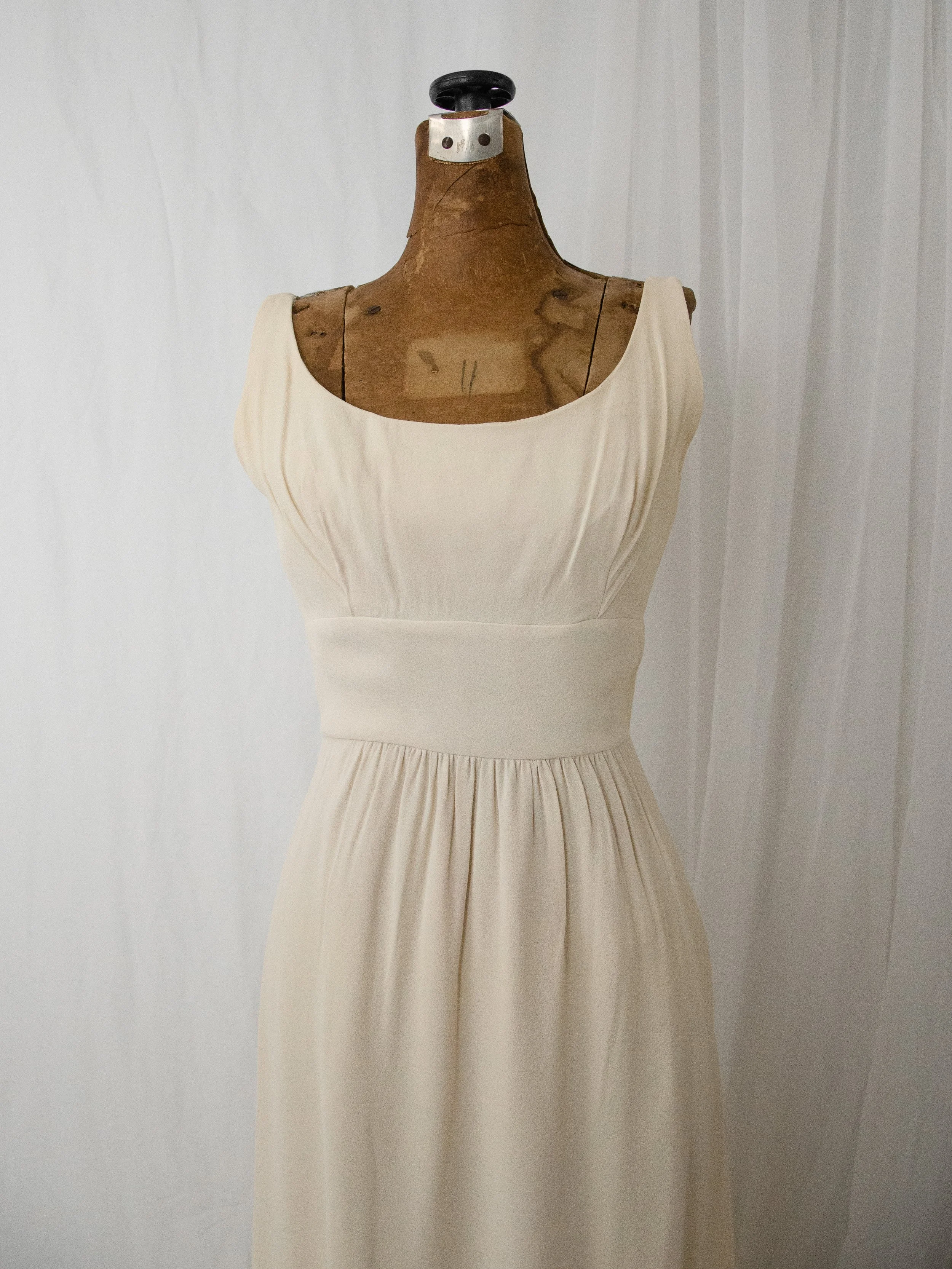 Close-up of the late 1950s cream crepe gown bodice on a dress form, showing the scoop neck and wide waistband.